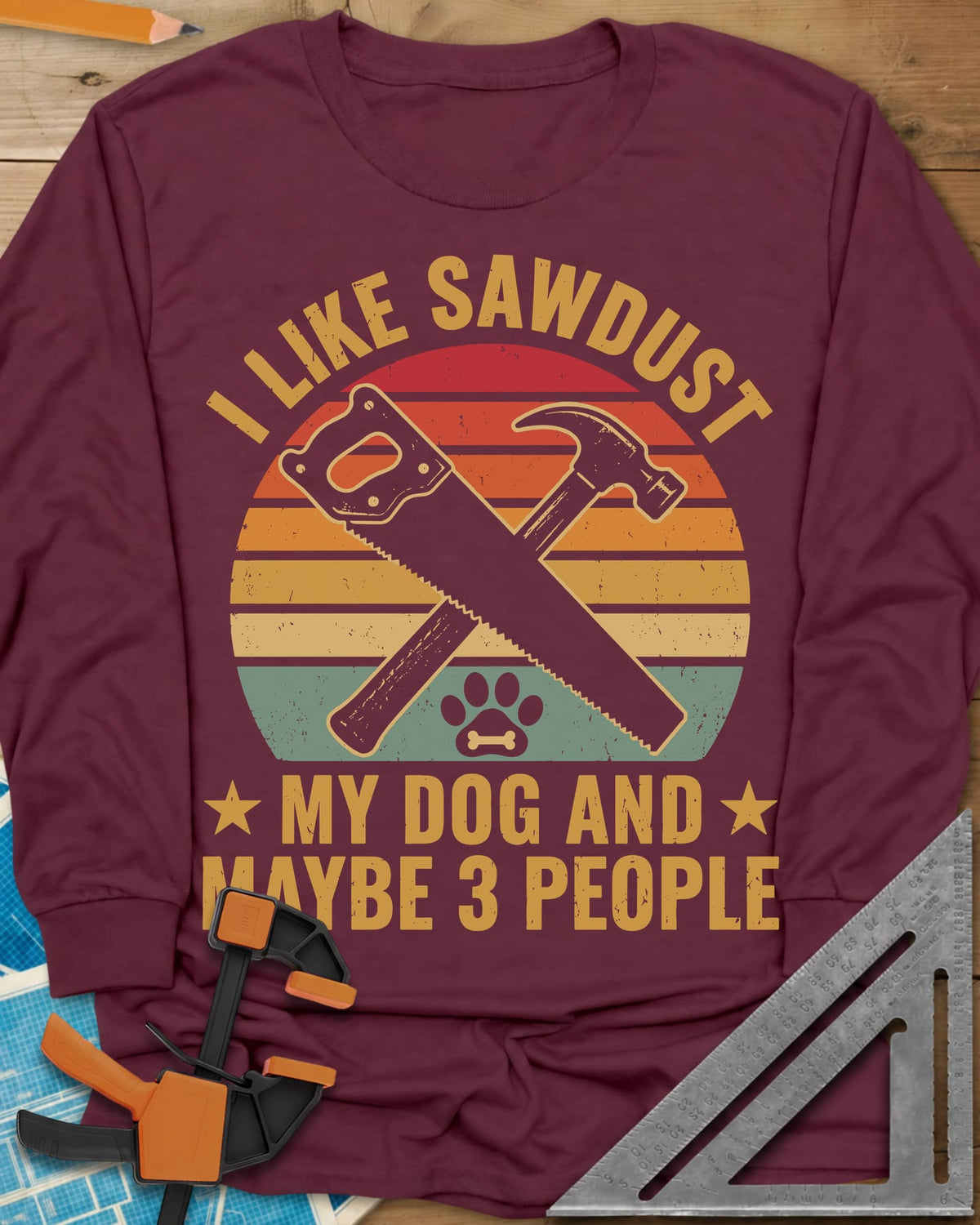 I Like Sawdust long sleeve shirt in Maroon, a hand saw crossed with a hammer over a paw print on retro stripes