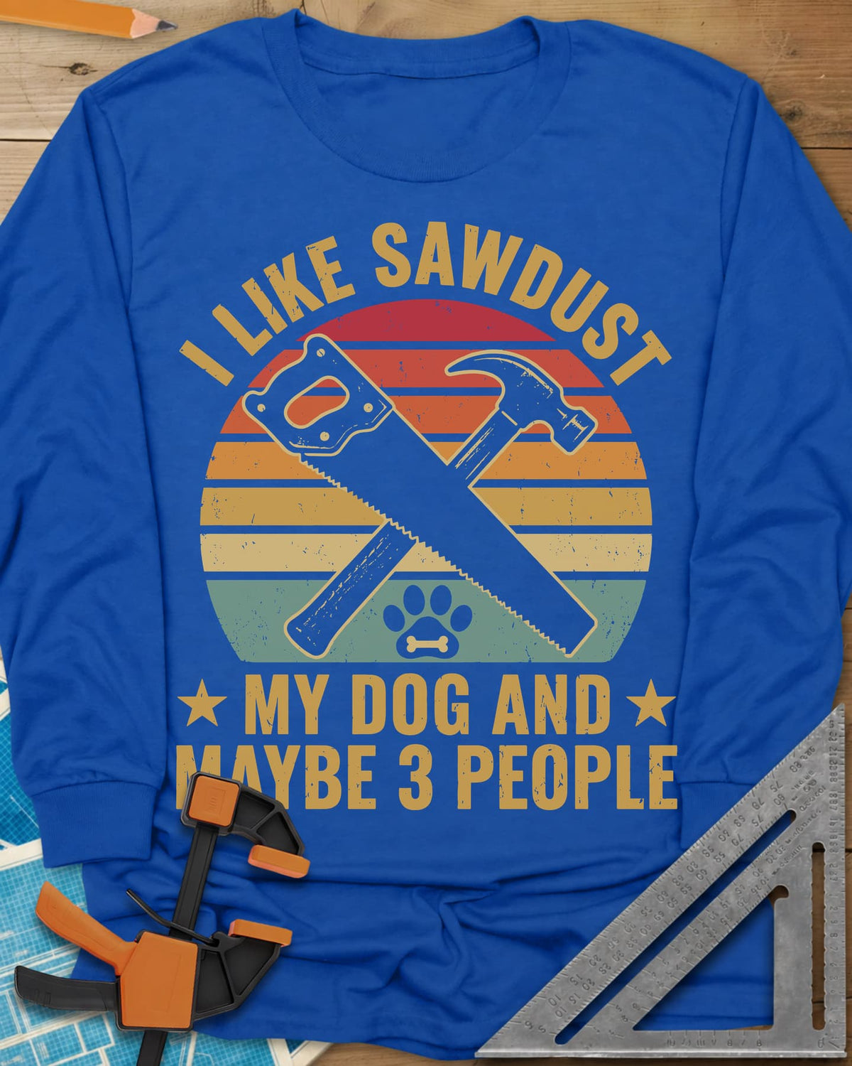 I Like Sawdust long sleeve shirt in Royal, a hand saw crossed with a hammer over a paw print on retro stripes
