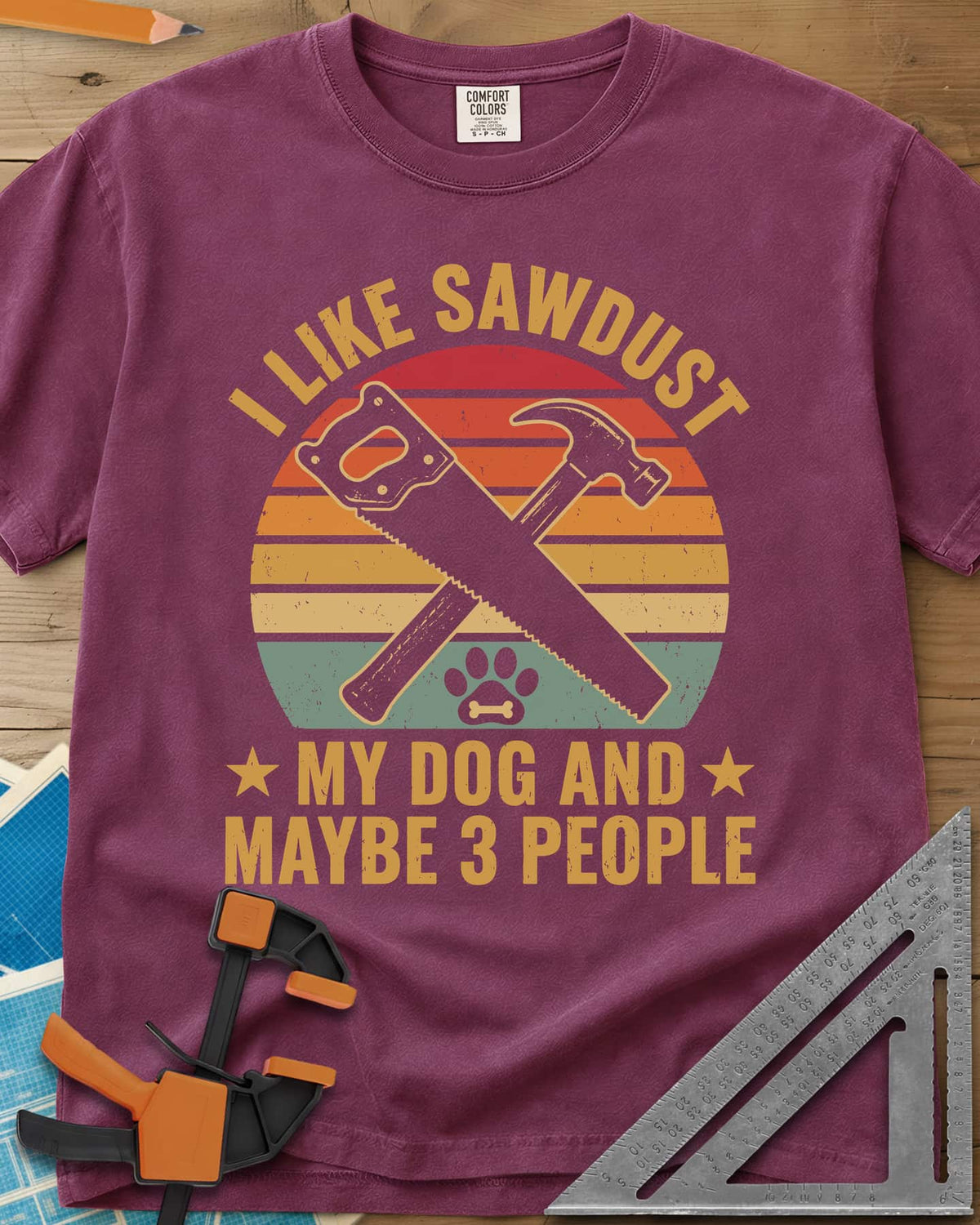 I Like Sawdust heavyweight tee in Berry, a hand saw crossed with a hammer over a paw print on retro stripes