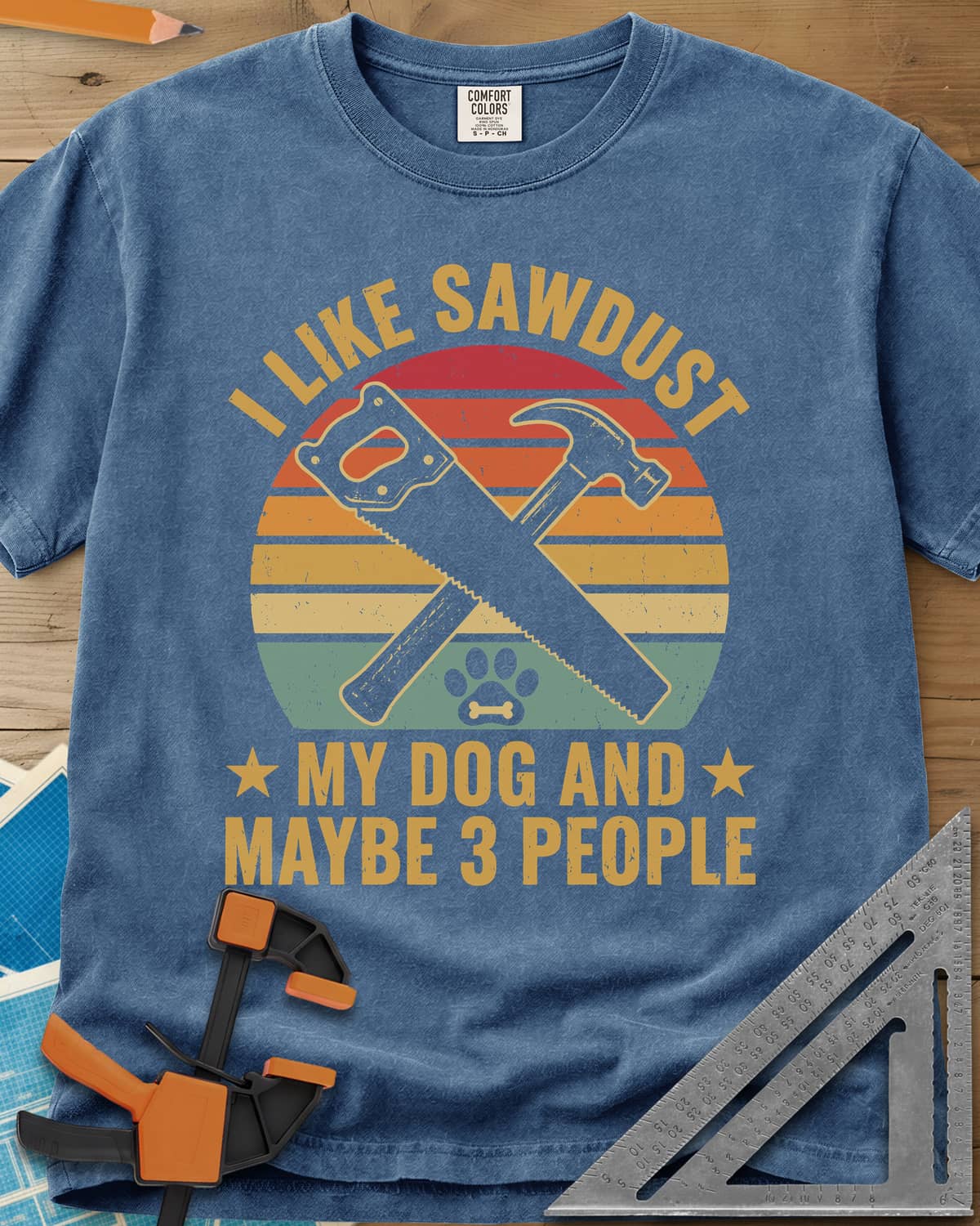 I Like Sawdust heavyweight tee in Blue Jean, a hand saw crossed with a hammer over a paw print on retro stripes