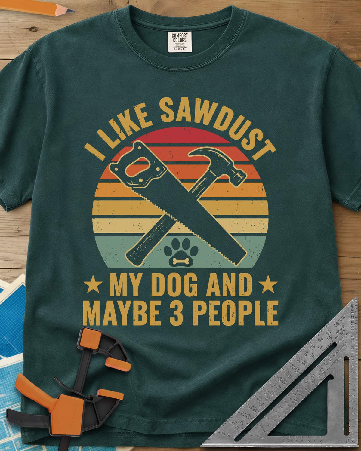 I Like Sawdust heavyweight tee in Blue Spruce, a hand saw crossed with a hammer over a paw print on retro stripes