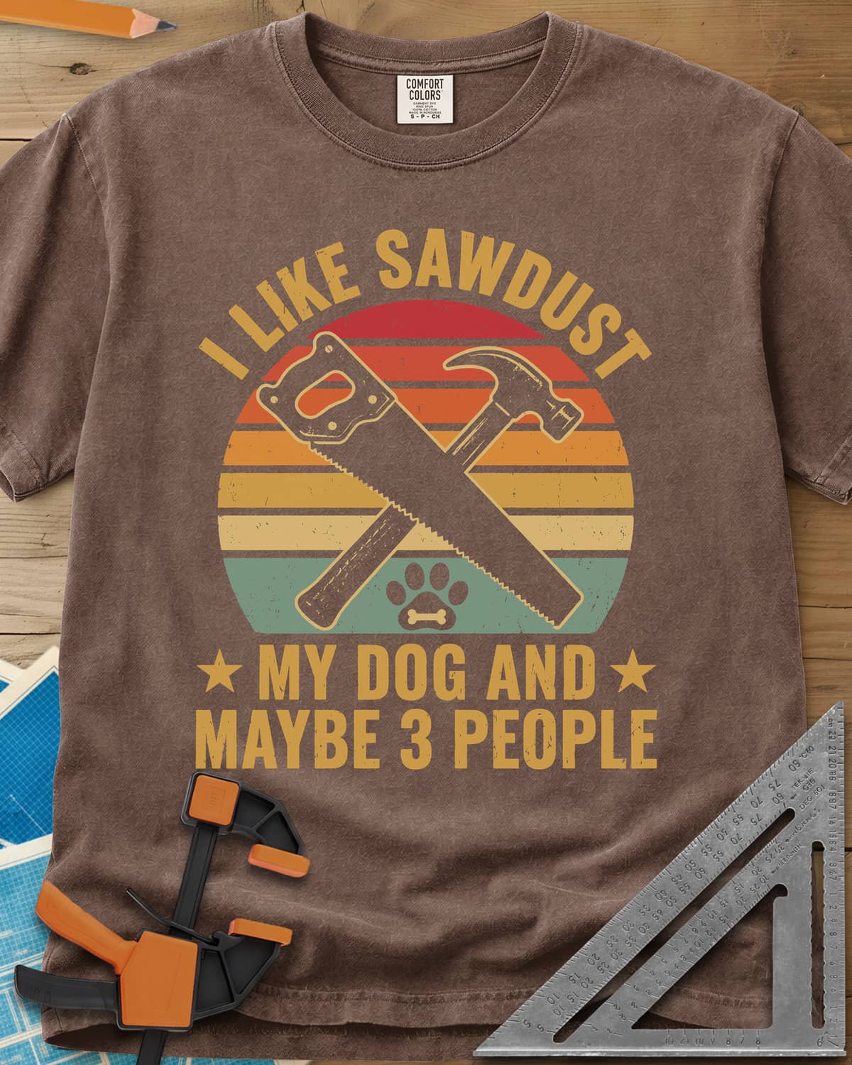 I Like Sawdust heavyweight tee in Espresso, a hand saw crossed with a hammer over a paw print on retro stripes