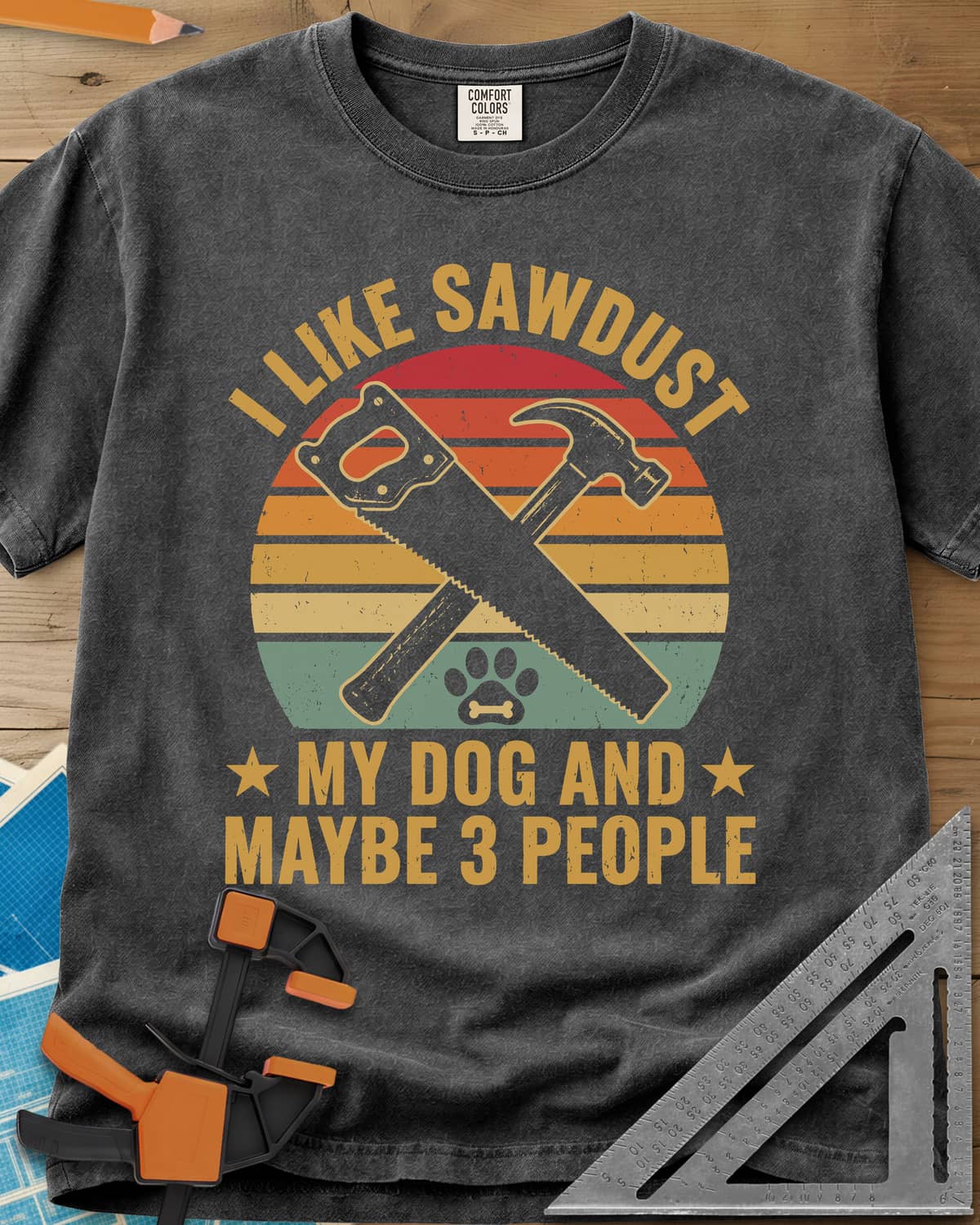 I Like Sawdust heavyweight tee in Pepper, a hand saw crossed with a hammer over a paw print on retro stripes