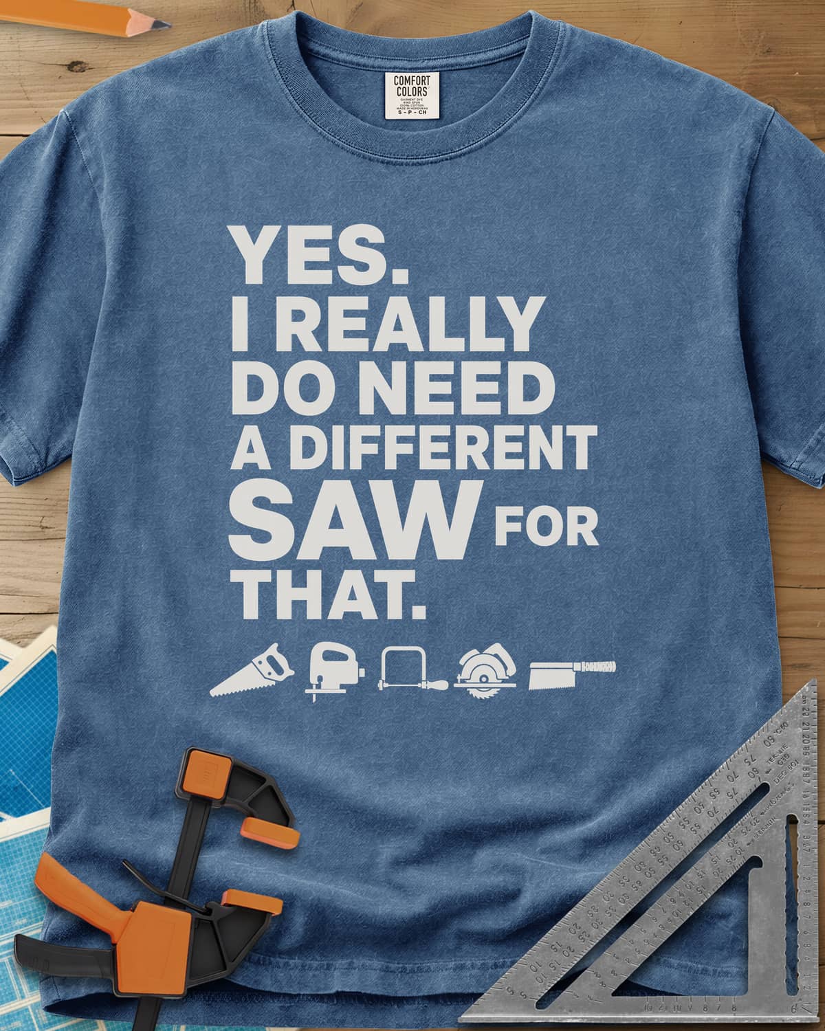 I Really Do Need A Different Saw heavyweight tee in Blue Jean, bold stacked lettering above a row of five small saw icons