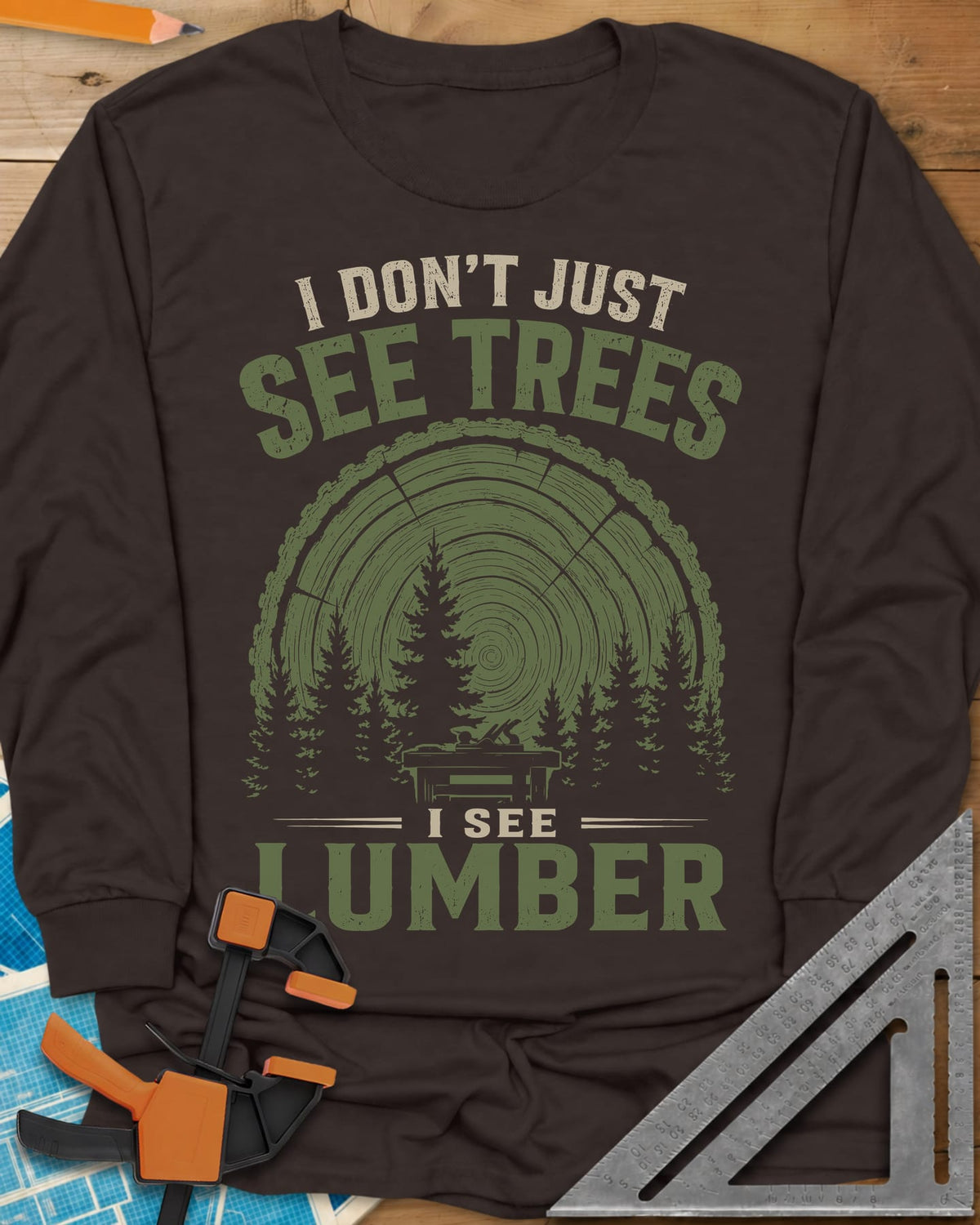 I See Lumber long sleeve shirt in Dark Chocolate, log growth rings, pine trees and a small workbench