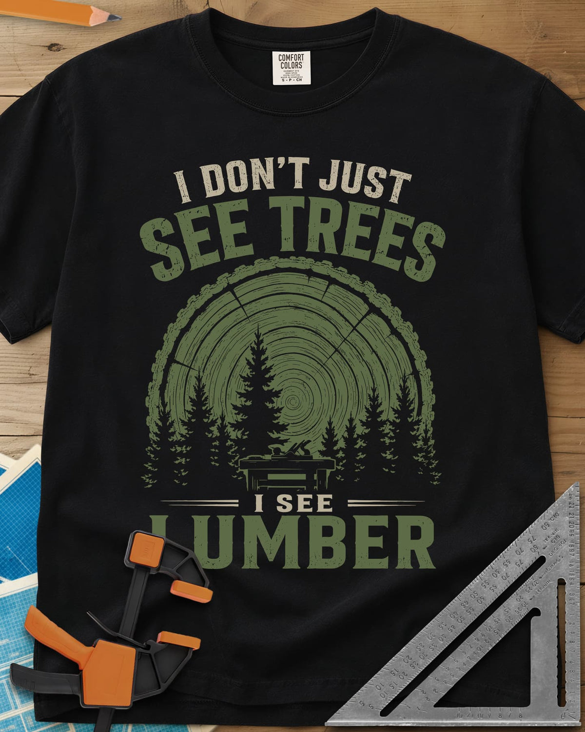 I See Lumber heavyweight tee in Black, log growth rings, pine trees and a small workbench