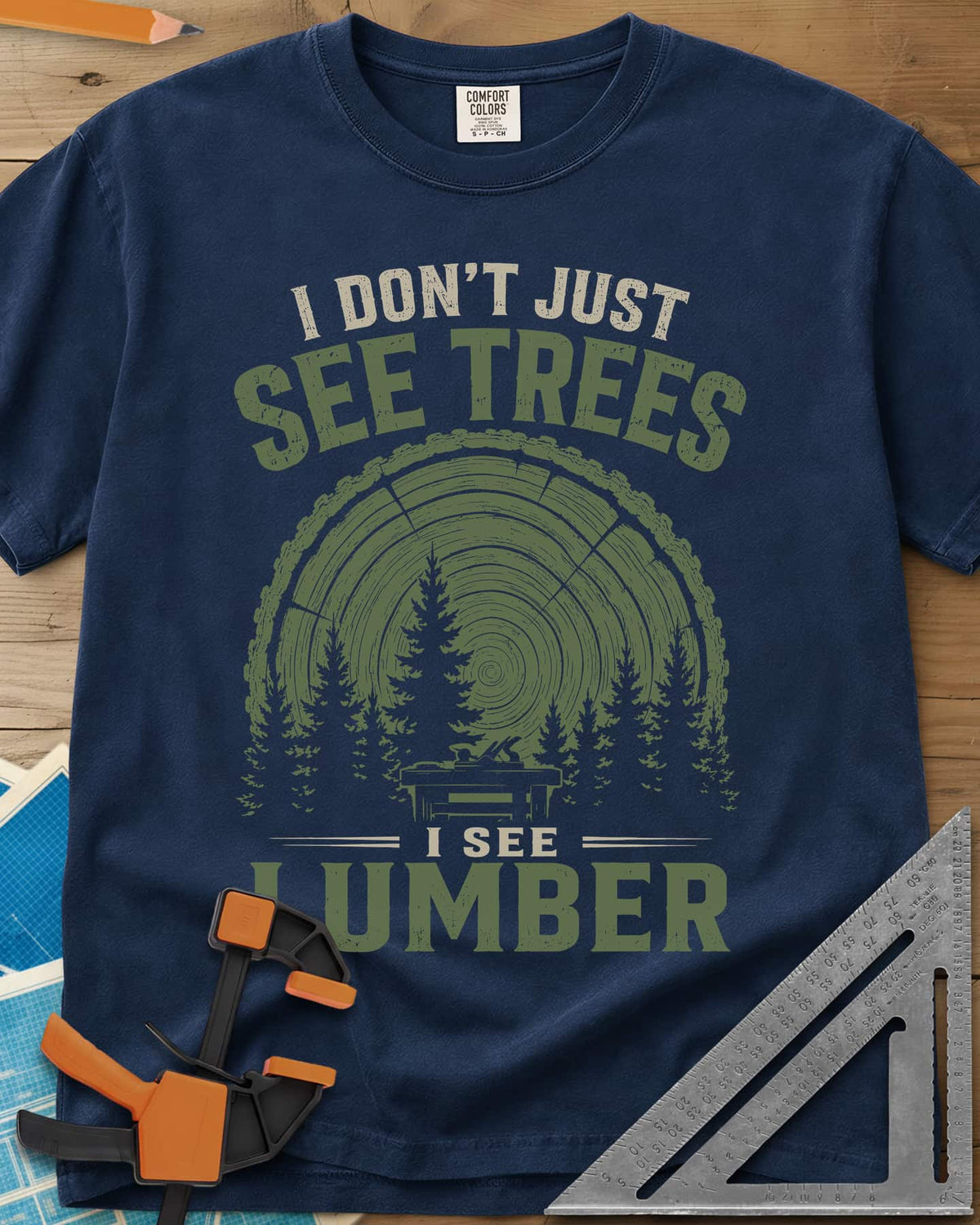 I See Lumber heavyweight tee in Navy, log growth rings, pine trees and a small workbench