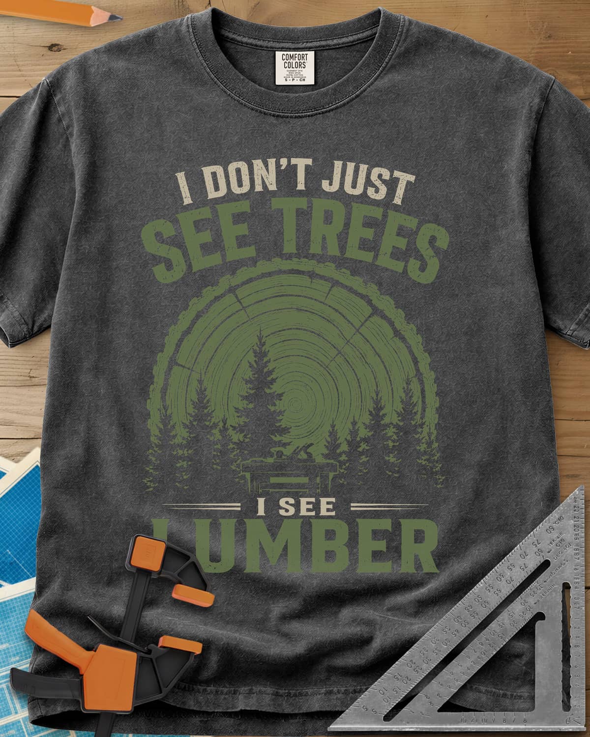 I See Lumber heavyweight tee in Pepper, log growth rings, pine trees and a small workbench
