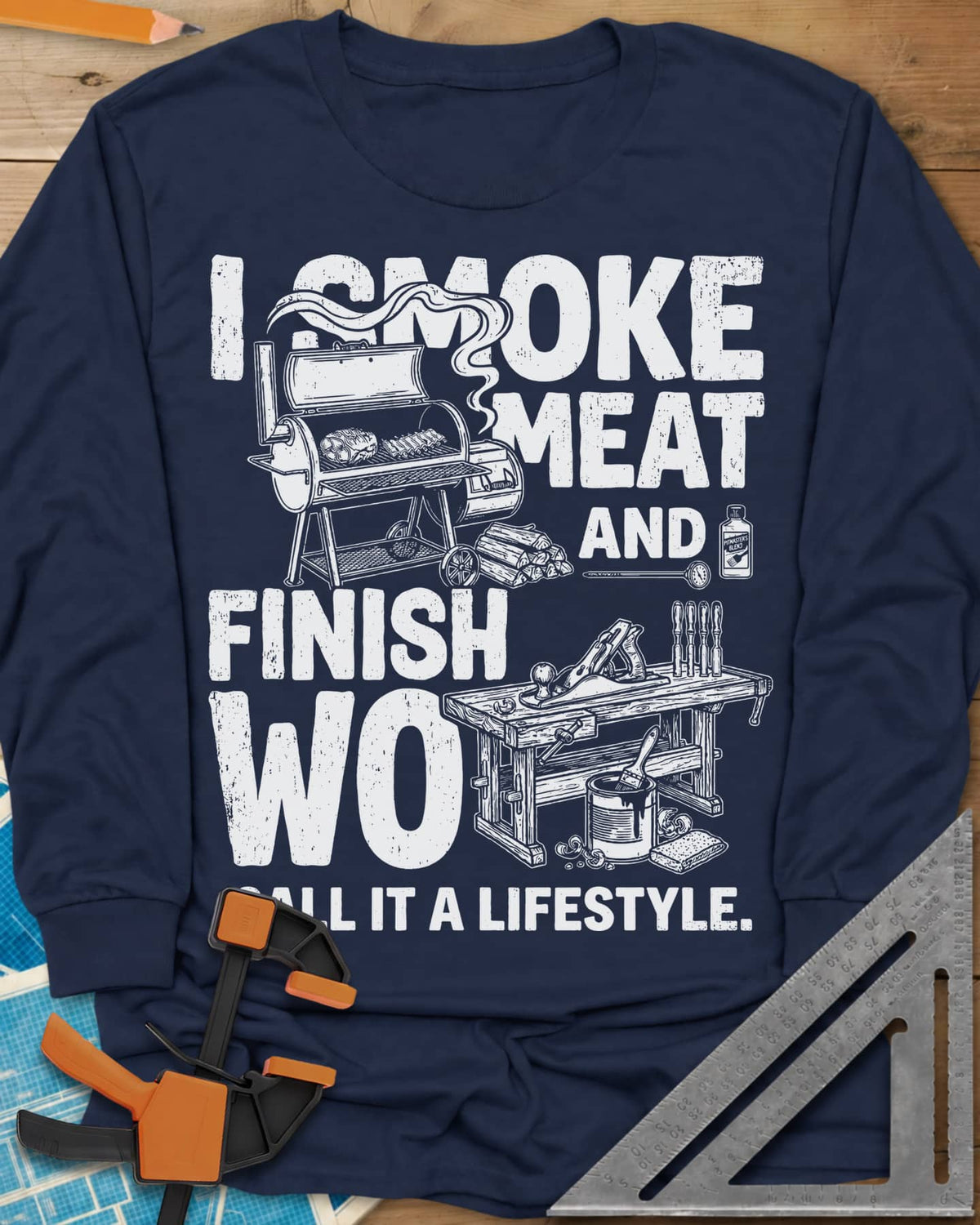 I Smoke Meat And Finish Wood long sleeve shirt in Navy, an offset smoker with ribs beside a workbench with a hand plane