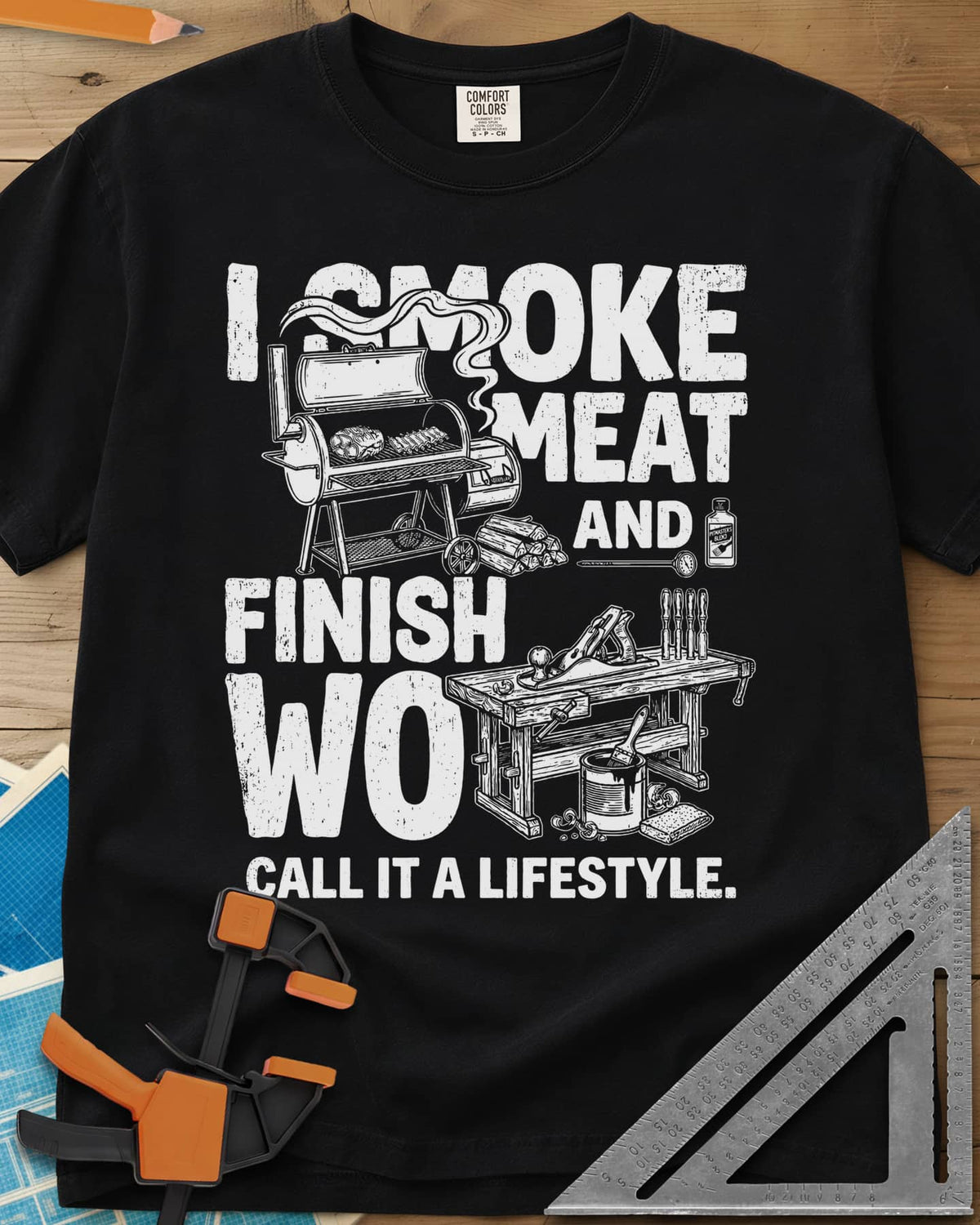 I Smoke Meat And Finish Wood heavyweight tee in Black, an offset smoker with ribs beside a workbench with a hand plane