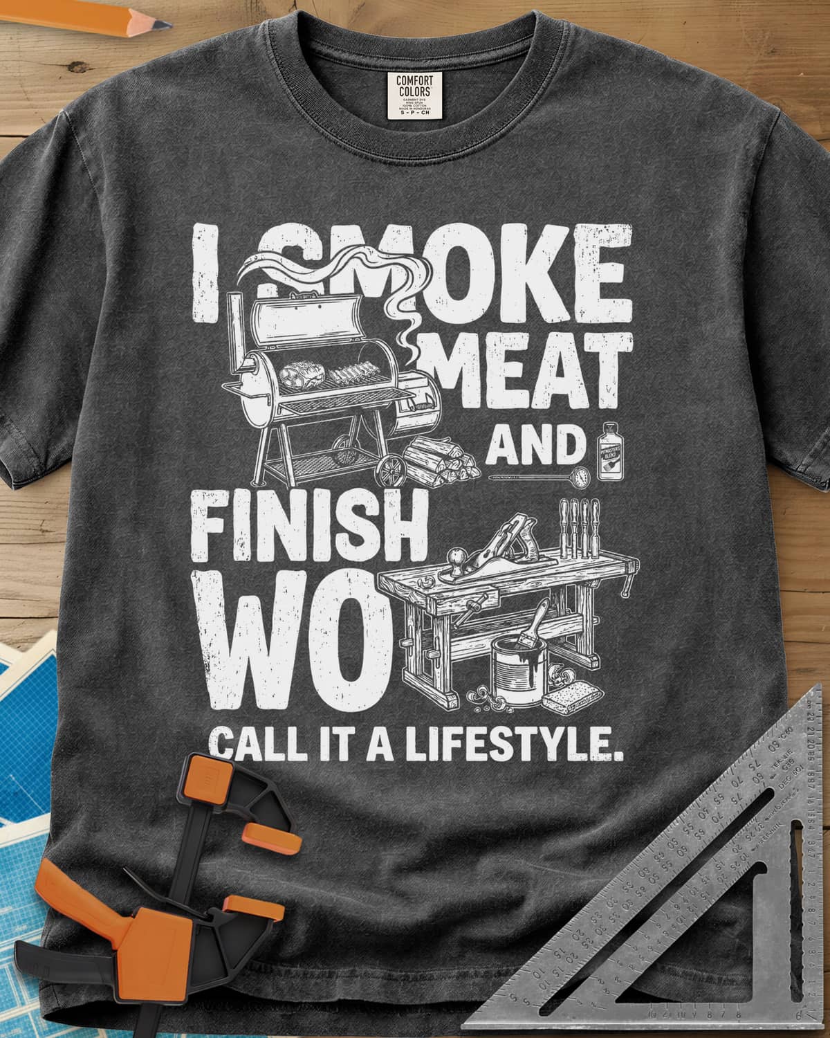I Smoke Meat And Finish Wood heavyweight tee in Pepper, an offset smoker with ribs beside a workbench with a hand plane