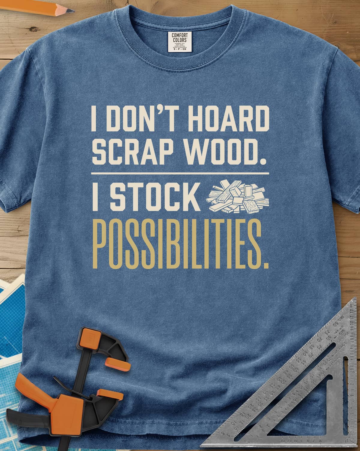 I Stock Possibilities heavyweight tee in Blue Jean, bold lettering beside a small pile of scrap wood offcuts