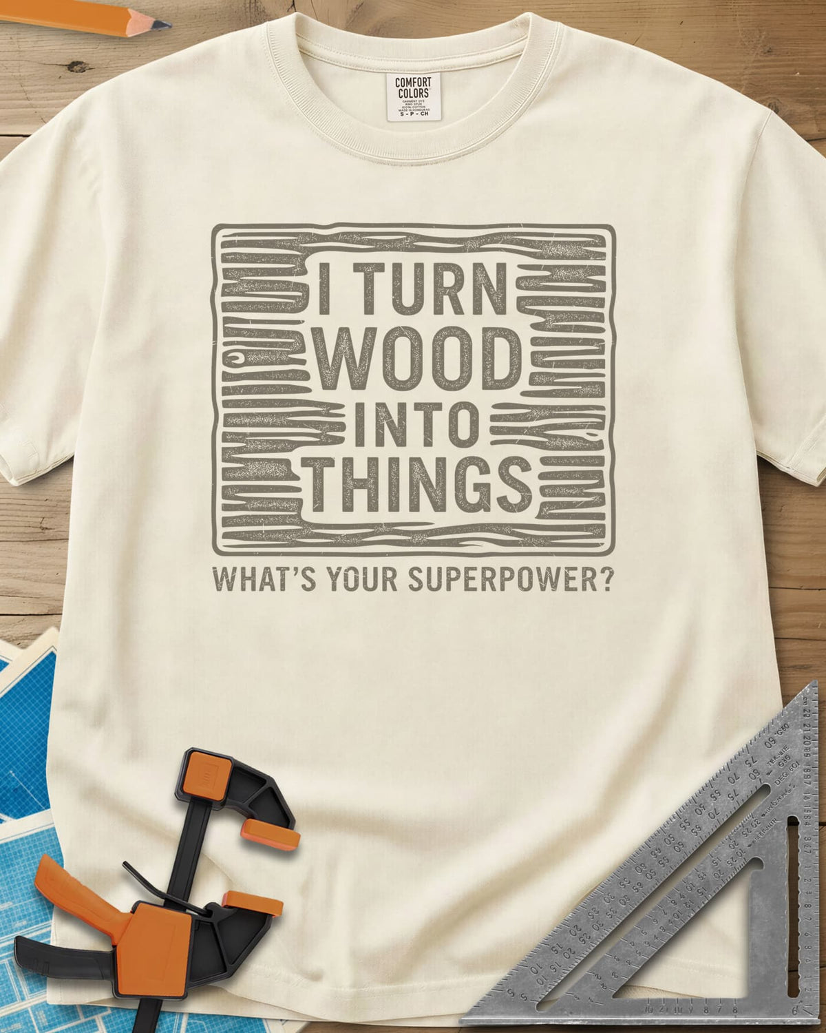 I Turn Wood Into Things heavyweight tee in Ivory, stacked block lettering inside a hand-drawn wood-grain frame