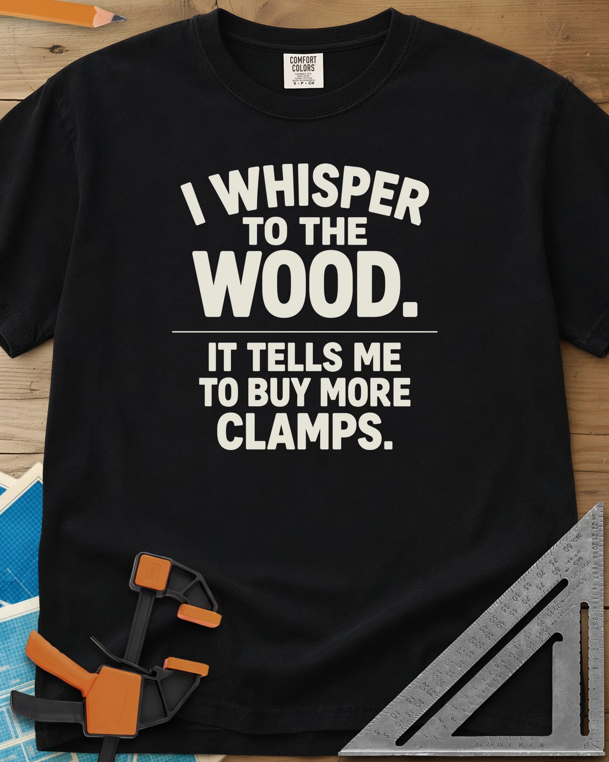 I Whisper To The Wood Clamp Humor heavyweight tee in Black, bold stacked lettering split by a thin divider line, no graphic