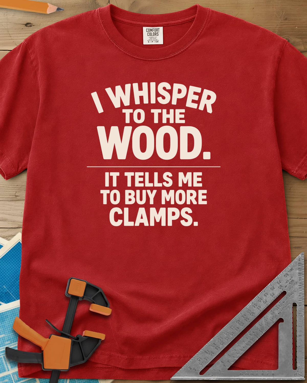 I Whisper To The Wood Clamp Humor heavyweight tee in Red, bold stacked lettering split by a thin divider line, no graphic