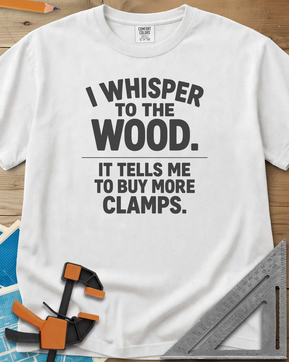 I Whisper To The Wood Clamp Humor heavyweight tee in White, bold stacked lettering split by a thin divider line, no graphic