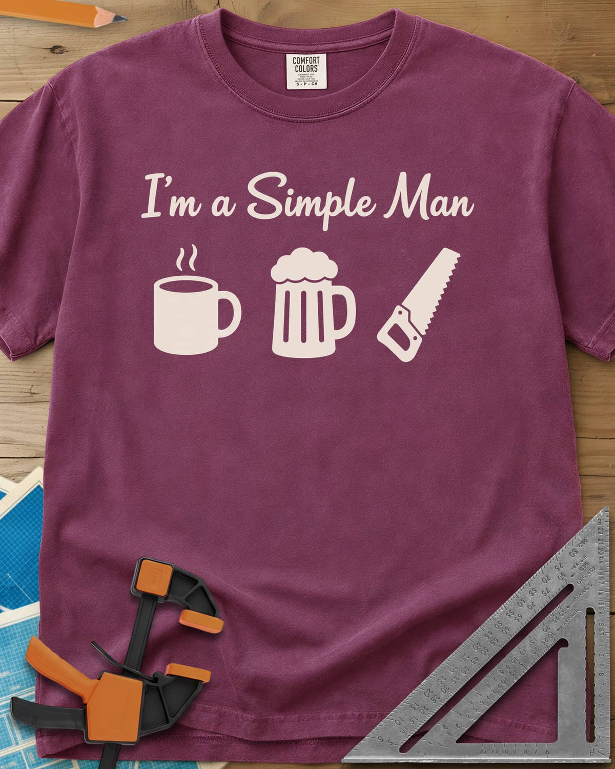 I’m A Simple Man Woodworking heavyweight tee in Berry, script headline over a steaming coffee mug, a beer mug and a handsaw