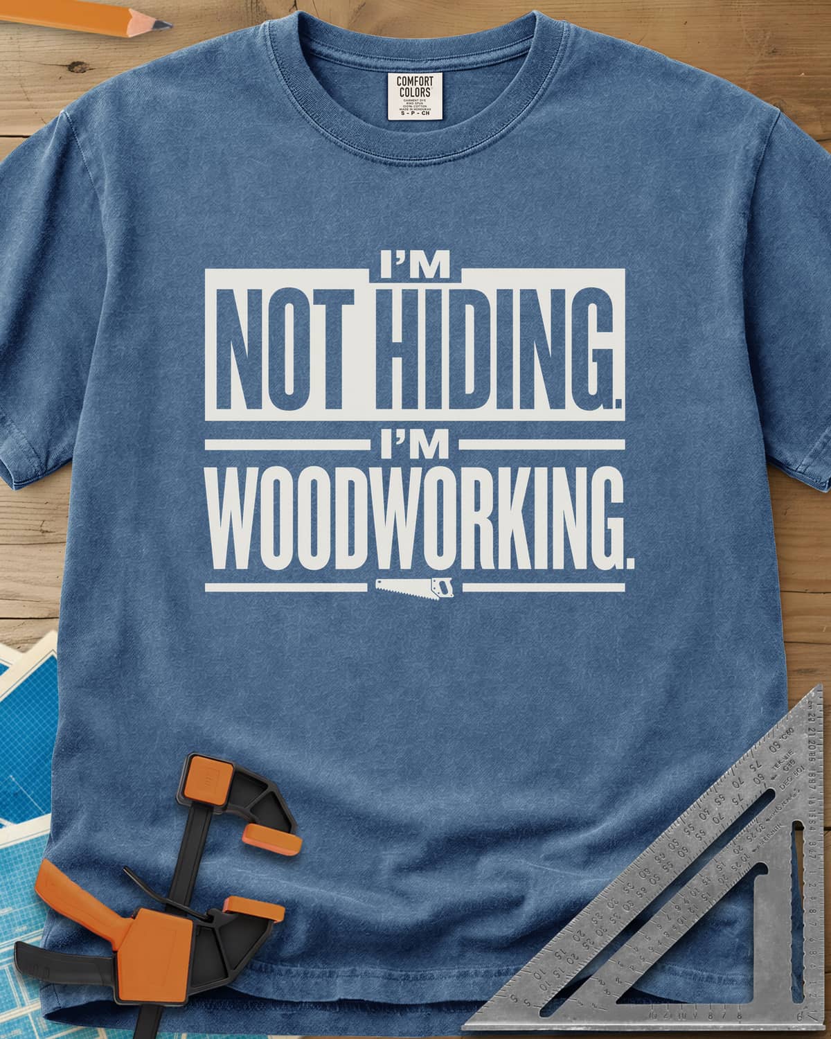 I'm Not Hiding I'm Woodworking heavyweight tee in Blue Jean, block lettering with a knocked-out box and a small handsaw