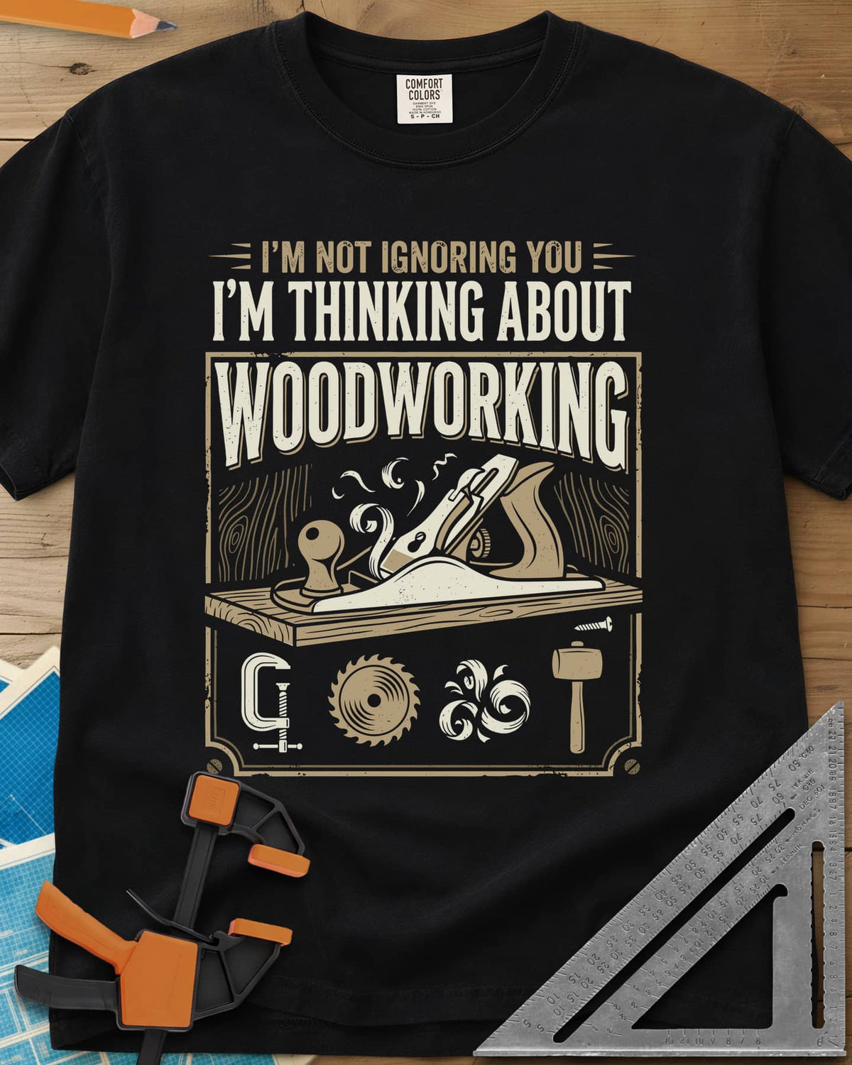 I'm Not Ignoring You I'm Thinking About Woodworking heavyweight tee in Black, a framed hand plane and shavings above clamp