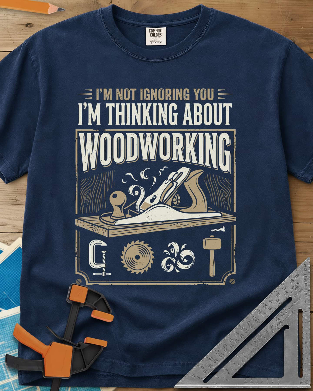 I'm Not Ignoring You I'm Thinking About Woodworking heavyweight tee in Navy, a framed hand plane and shavings above clamp