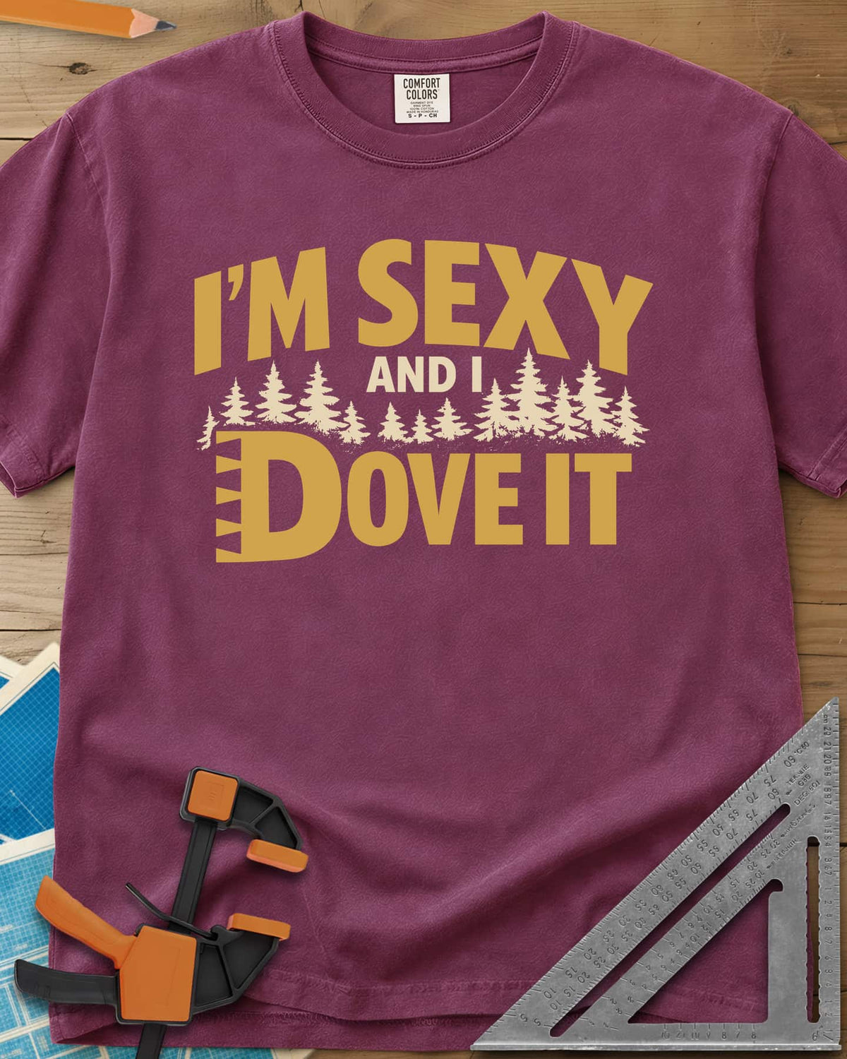 I'm Sexy and I Dove It heavyweight tee in Berry, gold block lettering, a row of pine trees and a notched D