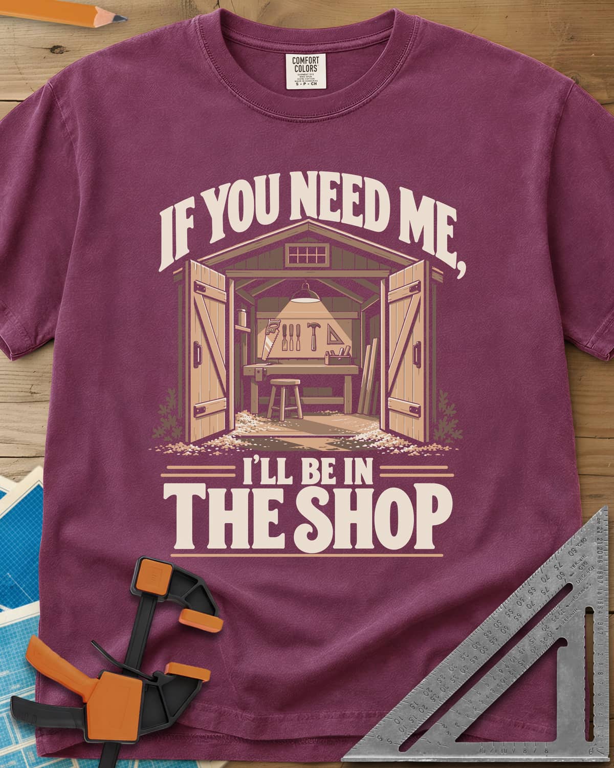 In The Shop heavyweight tee in Berry, a small open workshop with a hanging lamp, bench and wall tools