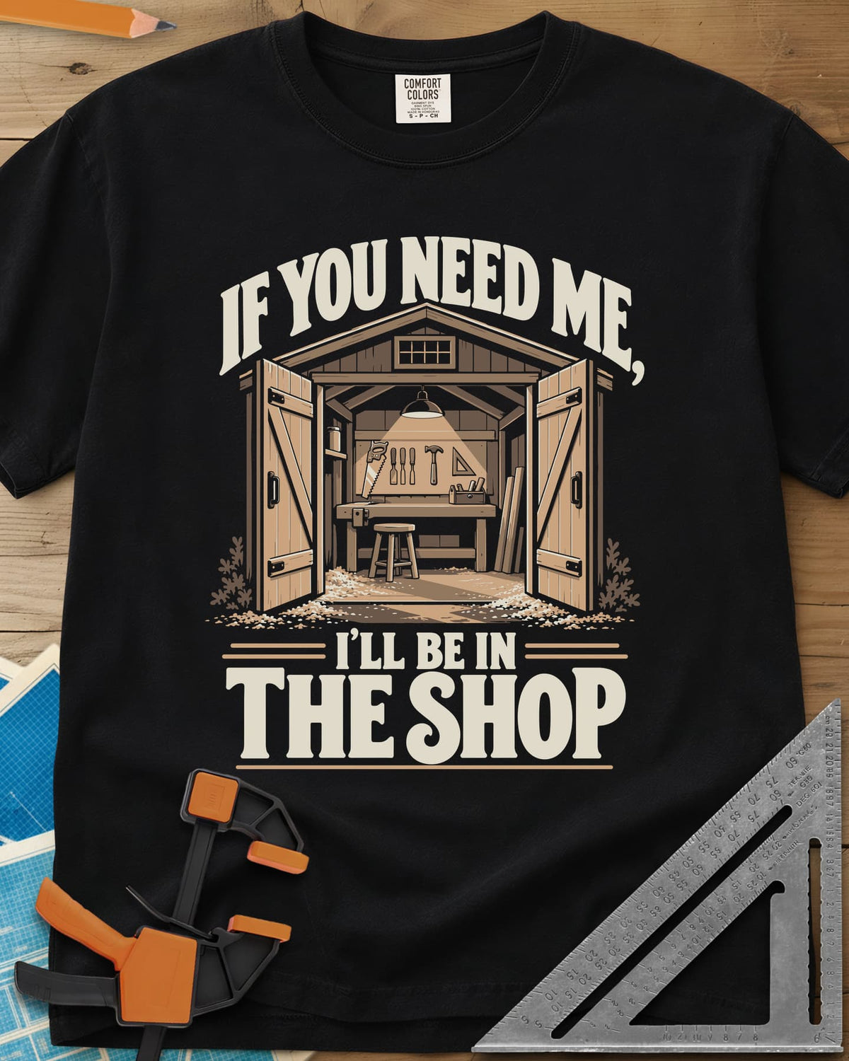 In The Shop heavyweight tee in Black, a small open workshop with a hanging lamp, bench and wall tools