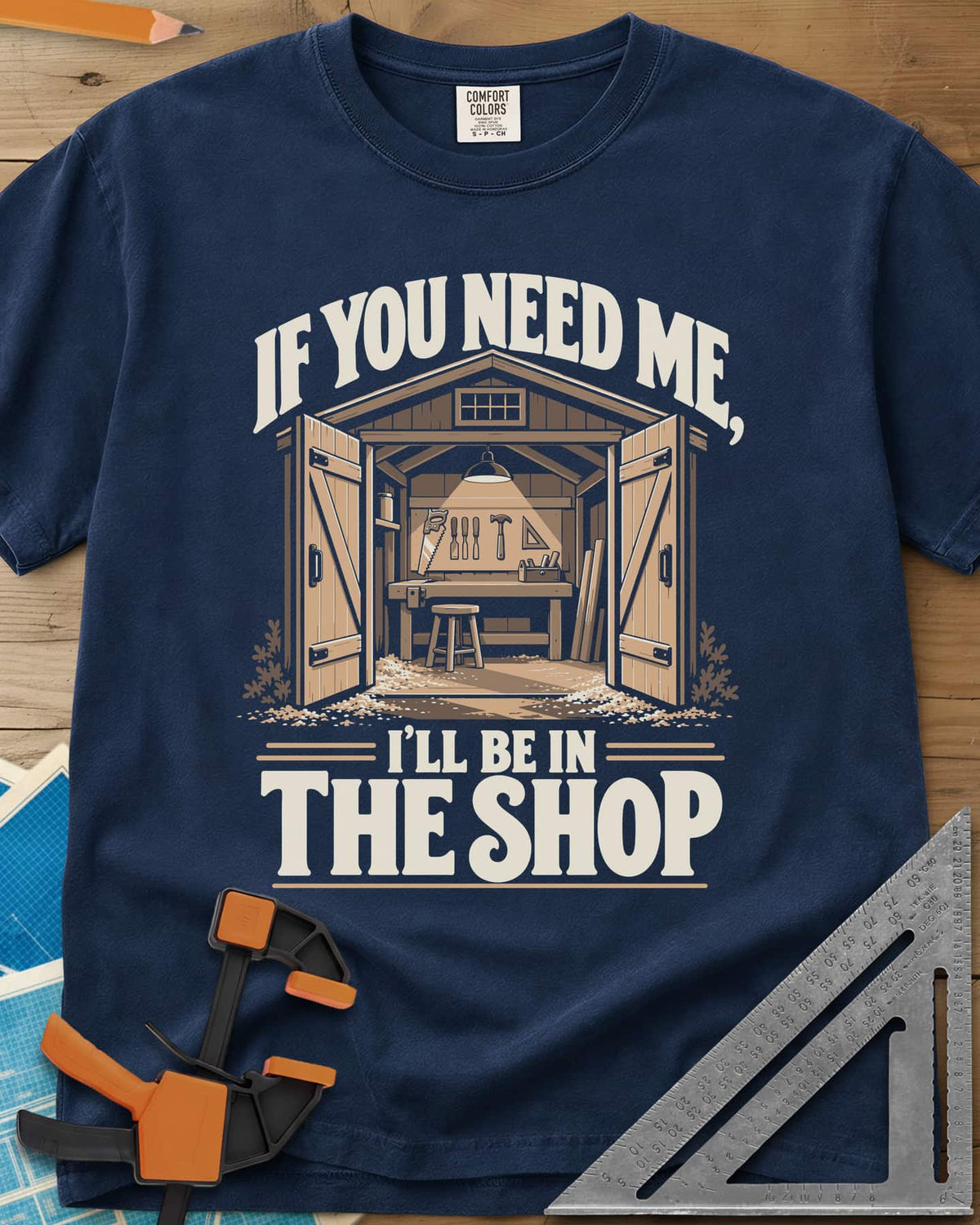 In The Shop heavyweight tee in Navy, a small open workshop with a hanging lamp, bench and wall tools