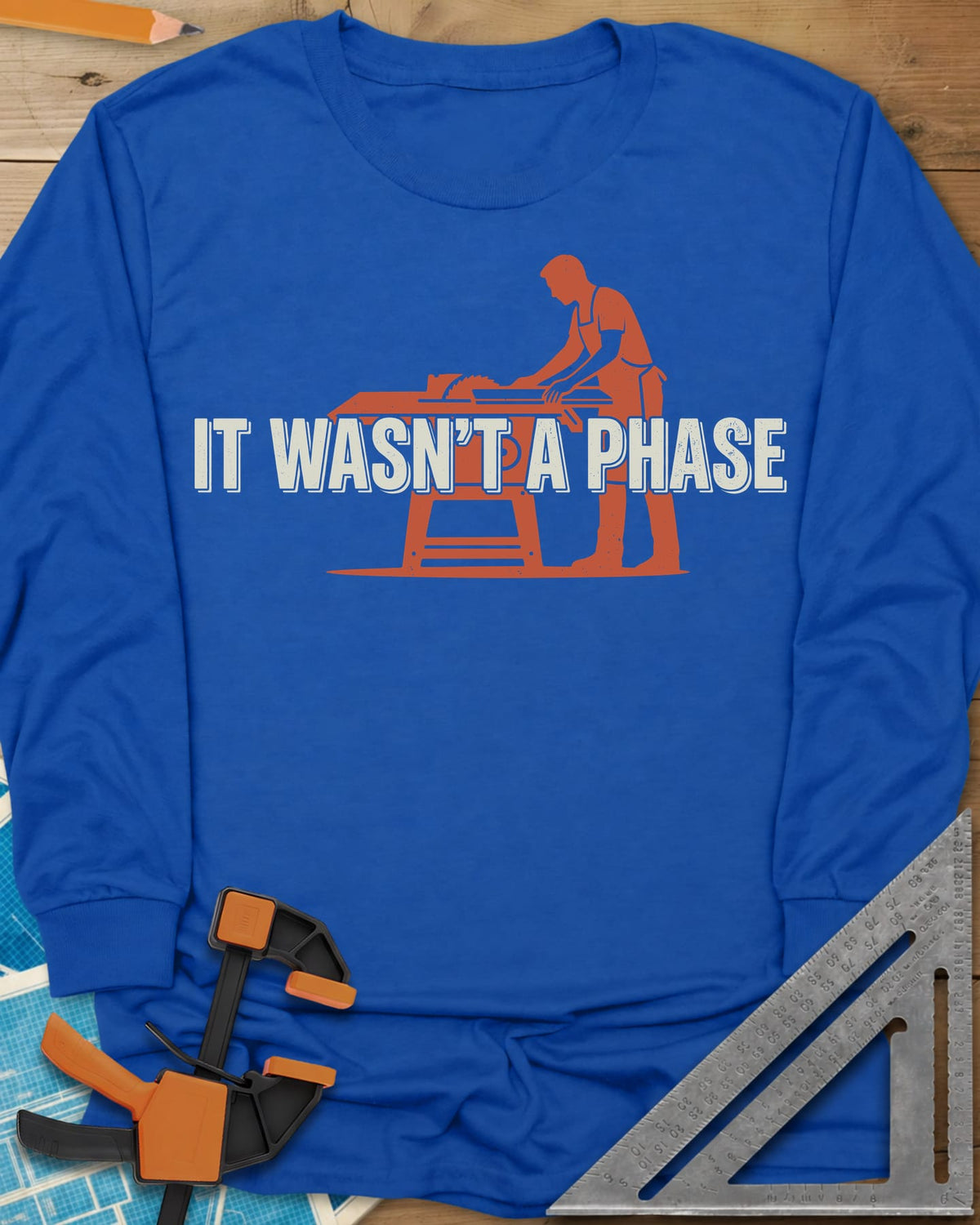It Was Not A Phase Woodworking long sleeve shirt in Royal, a rust-orange silhouette of a woodworker in an apron at a table