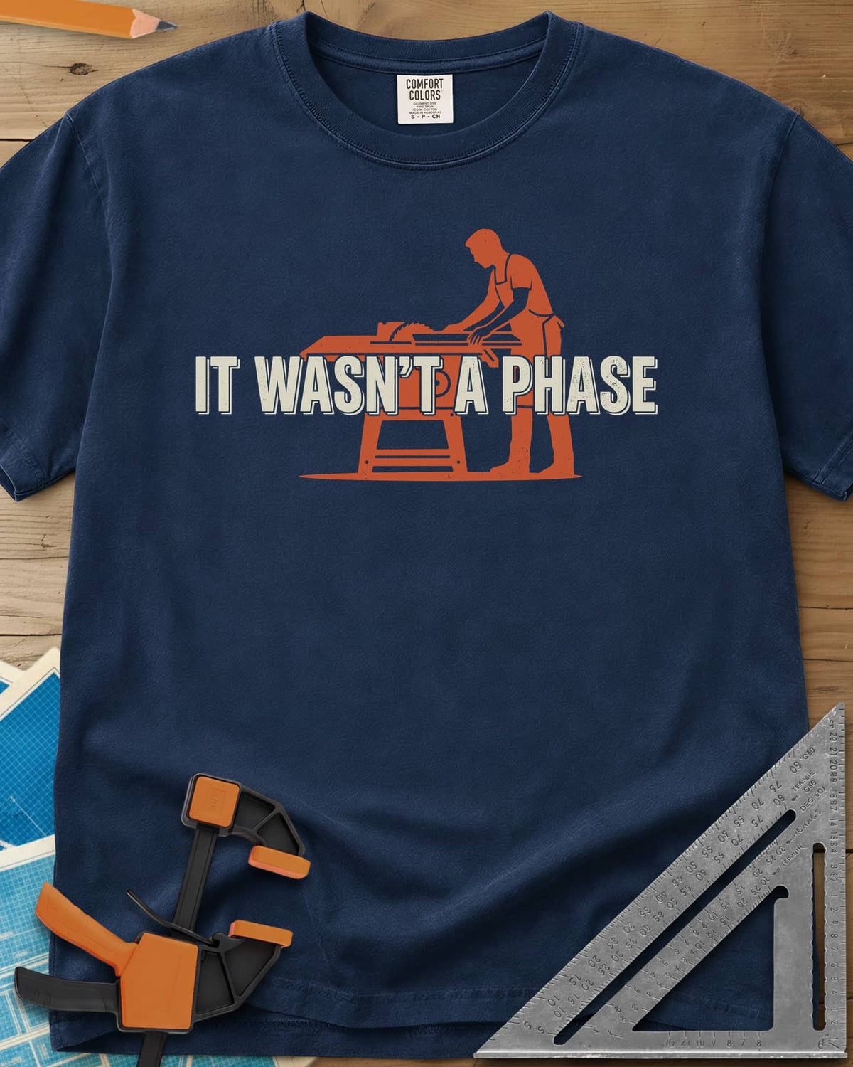 It Was Not A Phase Woodworking heavyweight tee in Navy, a rust-orange silhouette of a woodworker in an apron at a table saw