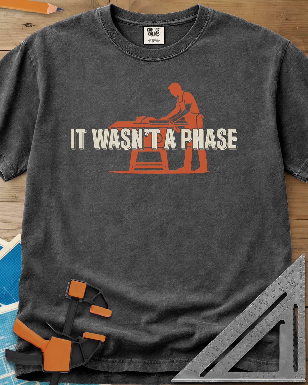 It Was Not A Phase Woodworking heavyweight tee in Pepper, a rust-orange silhouette of a woodworker in an apron at a table saw