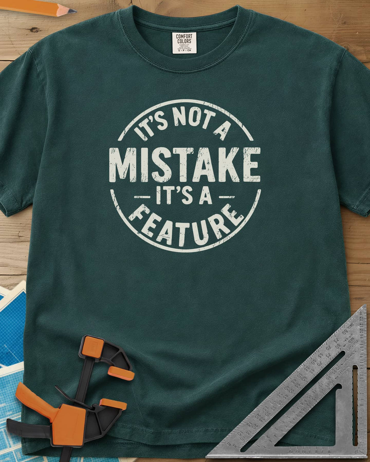 It's Not a Mistake heavyweight tee in Blue Spruce, a worn circular stamp with MISTAKE in large letters at the center
