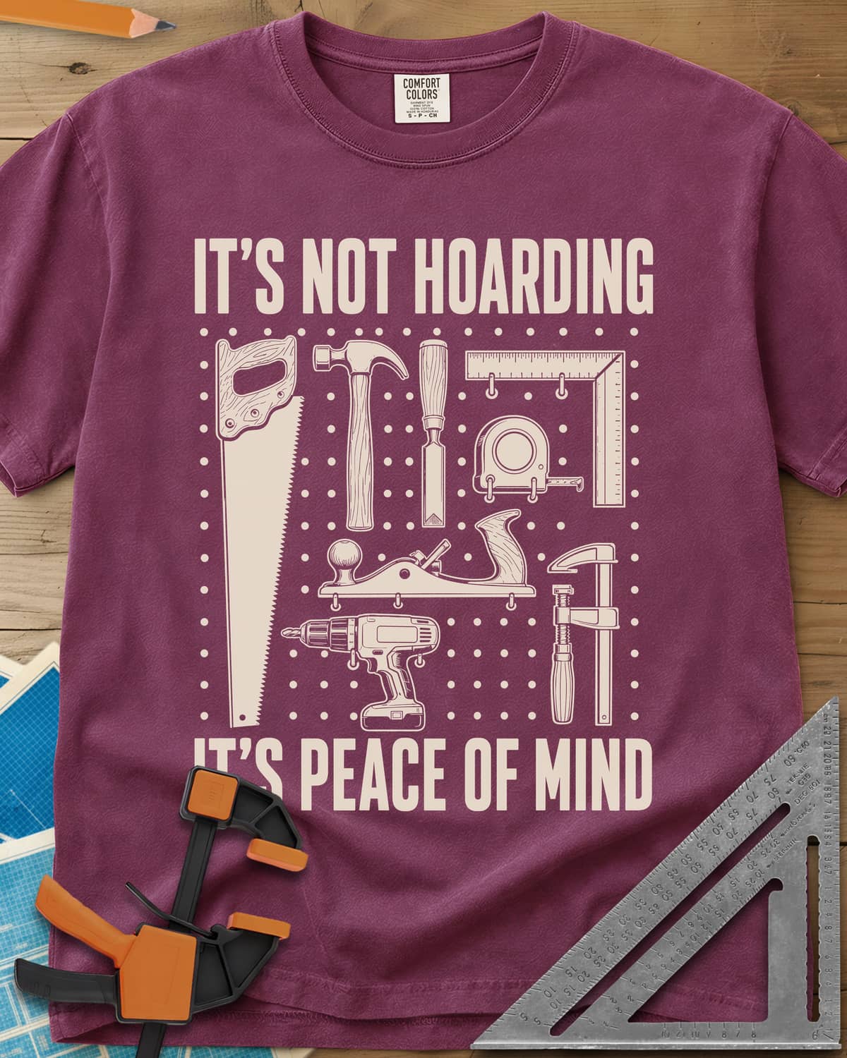 It's Not Hoarding It's Peace Of Mind heavyweight tee in Berry, a dotted pegboard grid of hand tools and a cordless drill