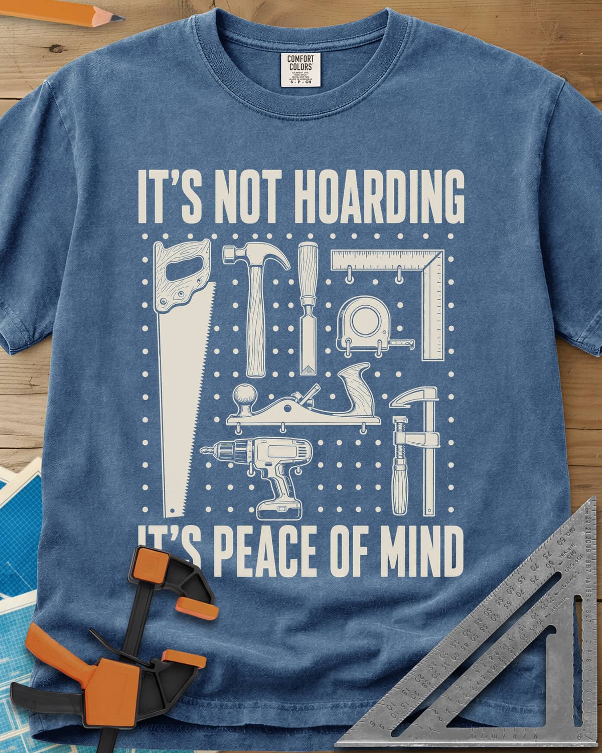 It's Not Hoarding It's Peace Of Mind heavyweight tee in Blue Jean, a dotted pegboard grid of hand tools and a cordless drill