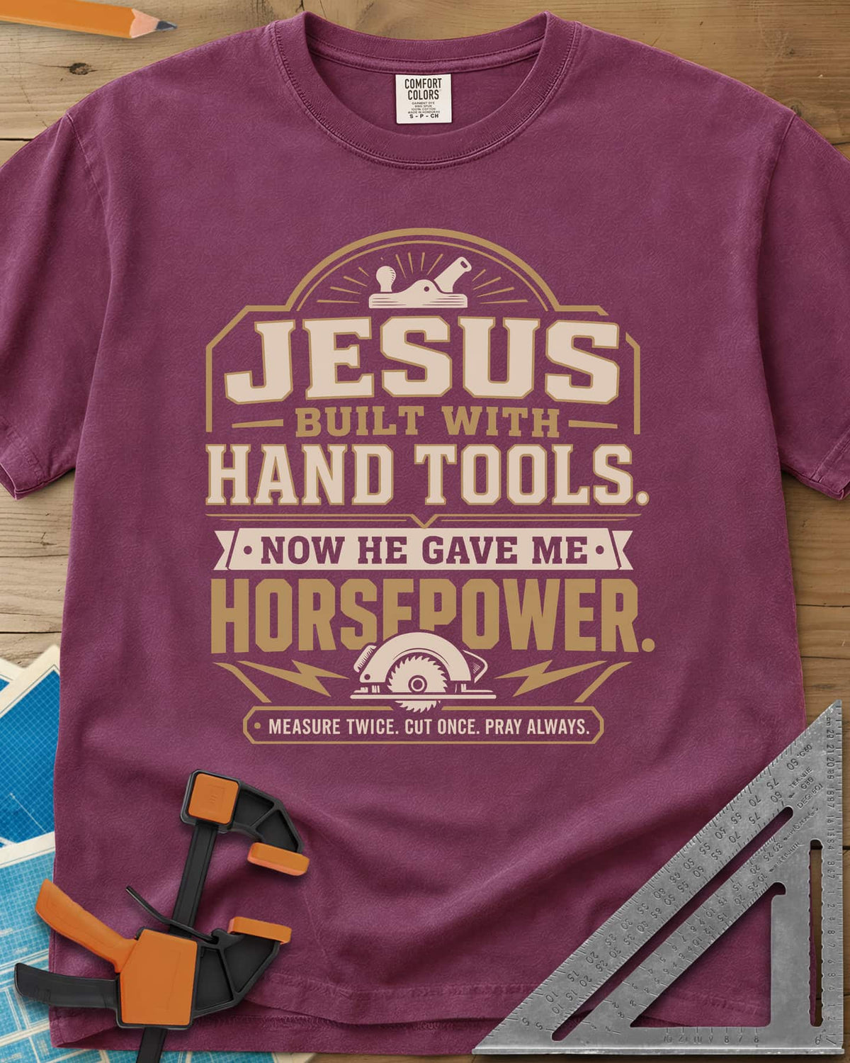 Jesus Built With Hand Tools heavyweight tee in Berry, a hand plane over bold lettering, a circular saw with bolts below