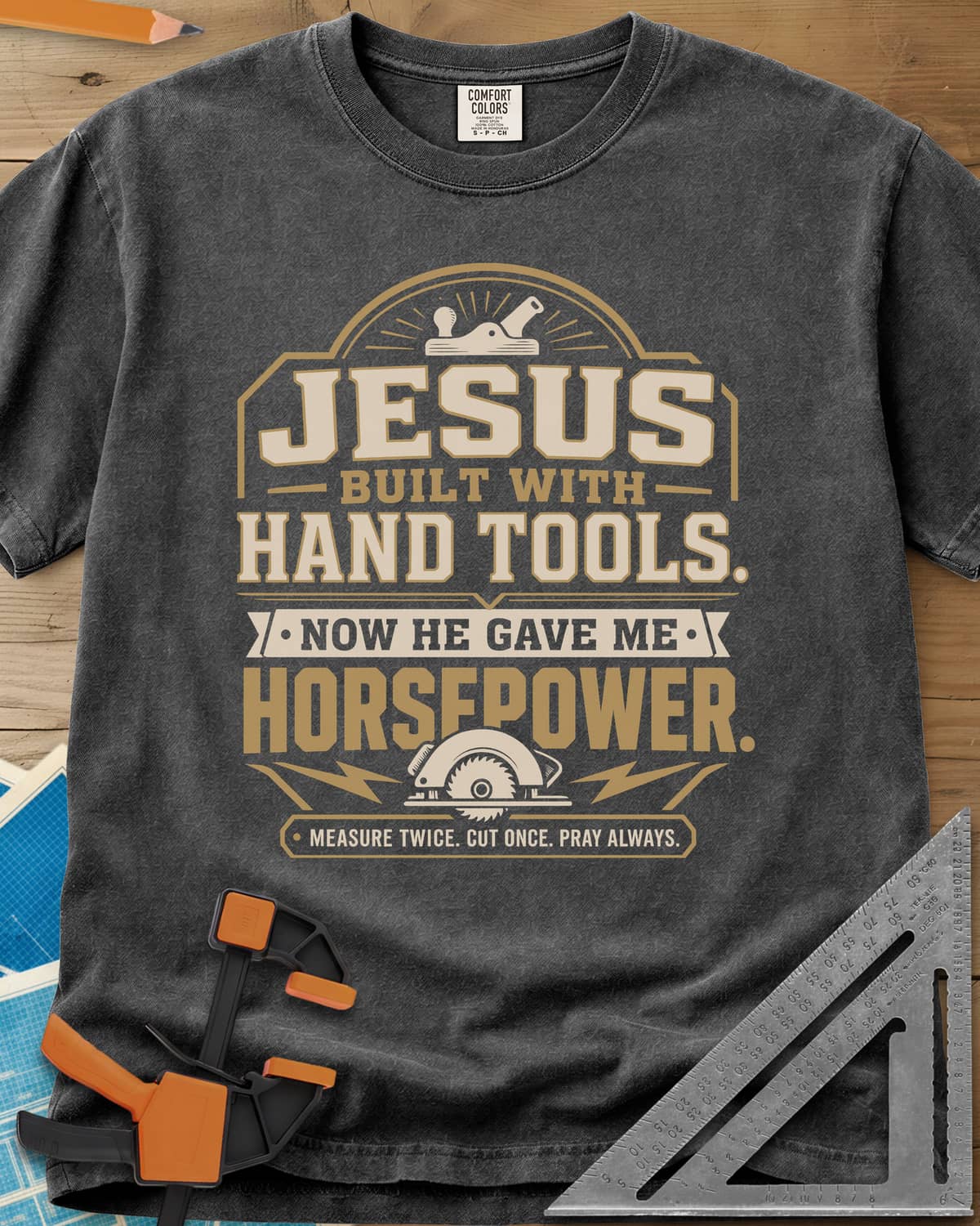 Jesus Built With Hand Tools heavyweight tee in Pepper, a hand plane over bold lettering, a circular saw with bolts below