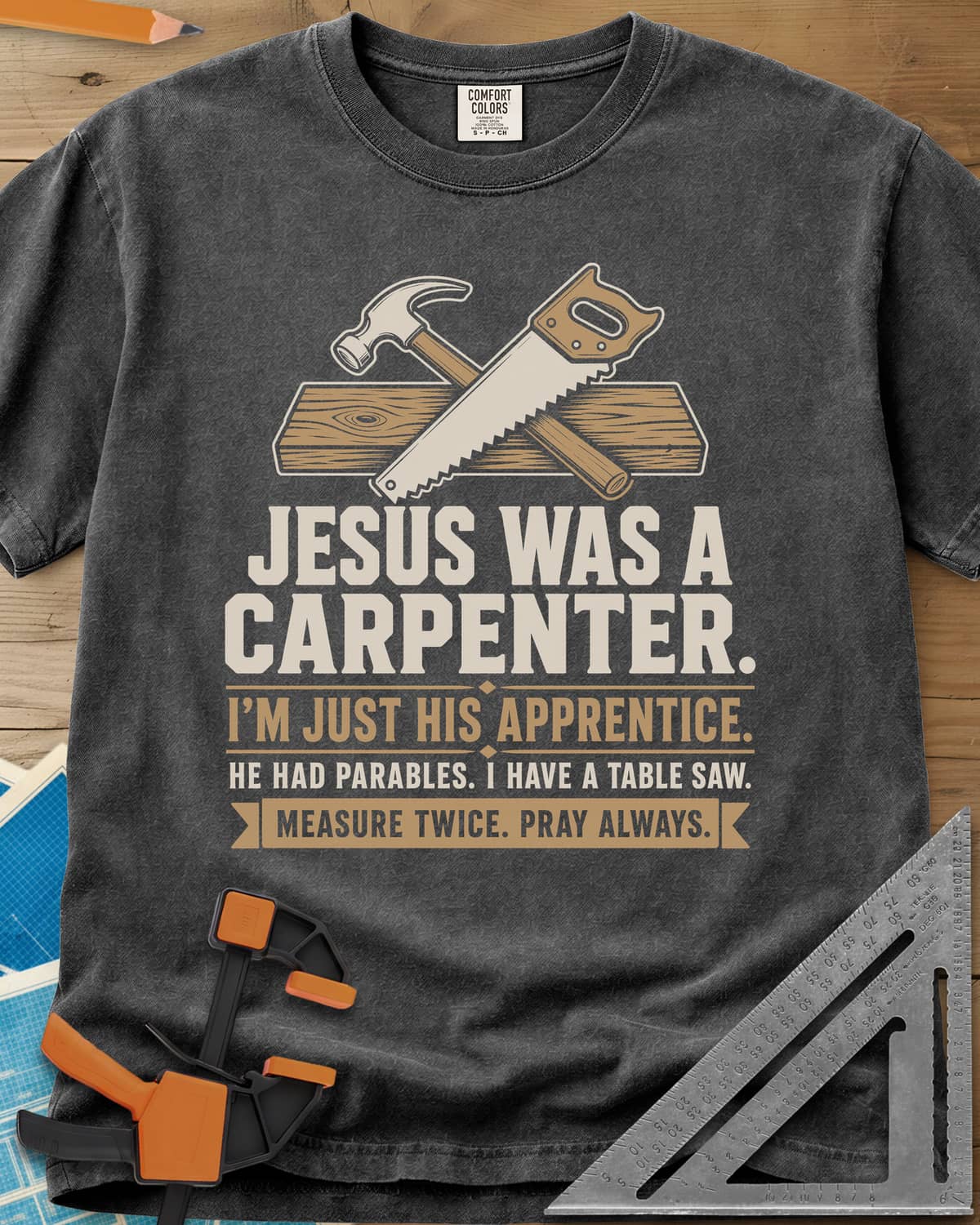 Jesus Was A Carpenter Apprentice heavyweight tee in Pepper, crossed hammer and hand saw over a plank, with stacked lettering