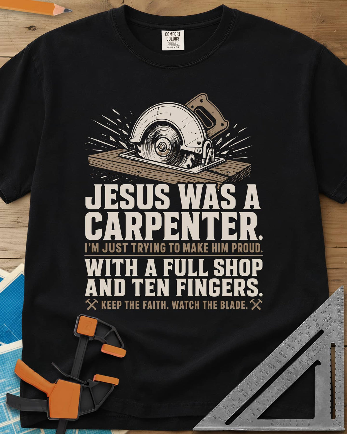 Jesus Was A Carpenter Proud heavyweight tee in Black, a circular saw cutting a board with sparks flying