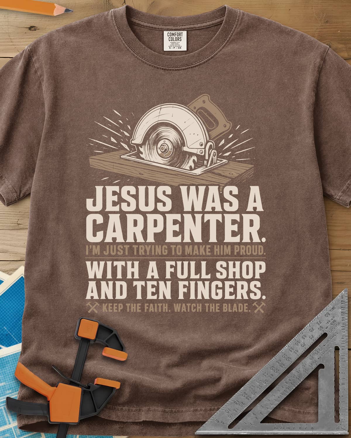 Jesus Was A Carpenter Proud heavyweight tee in Espresso, a circular saw cutting a board with sparks flying