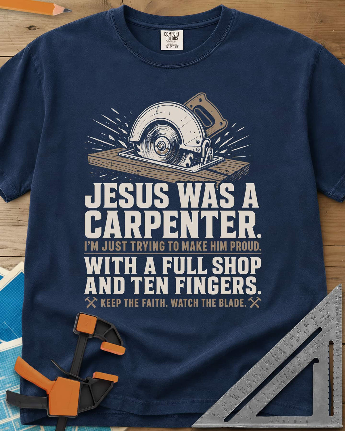 Jesus Was A Carpenter Proud heavyweight tee in Navy, a circular saw cutting a board with sparks flying