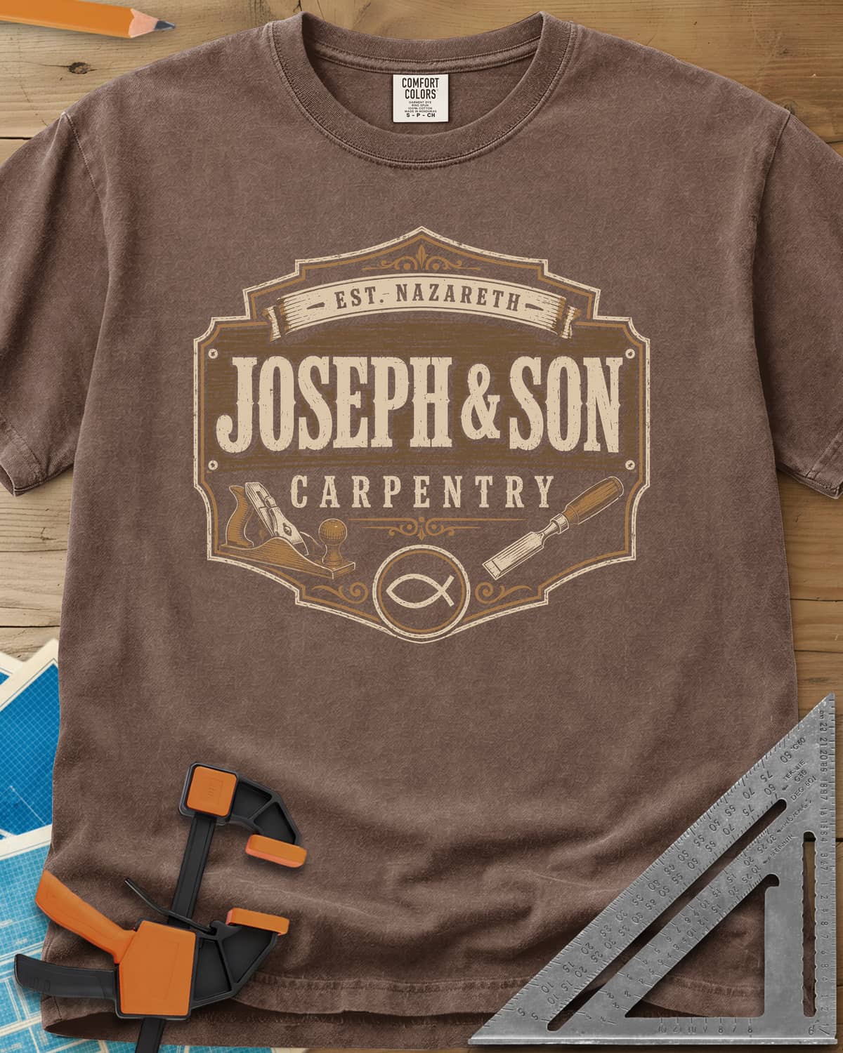 Joseph & Son Carpentry heavyweight tee in Espresso, a shop-sign badge with a hand plane, chisel and fish symbol