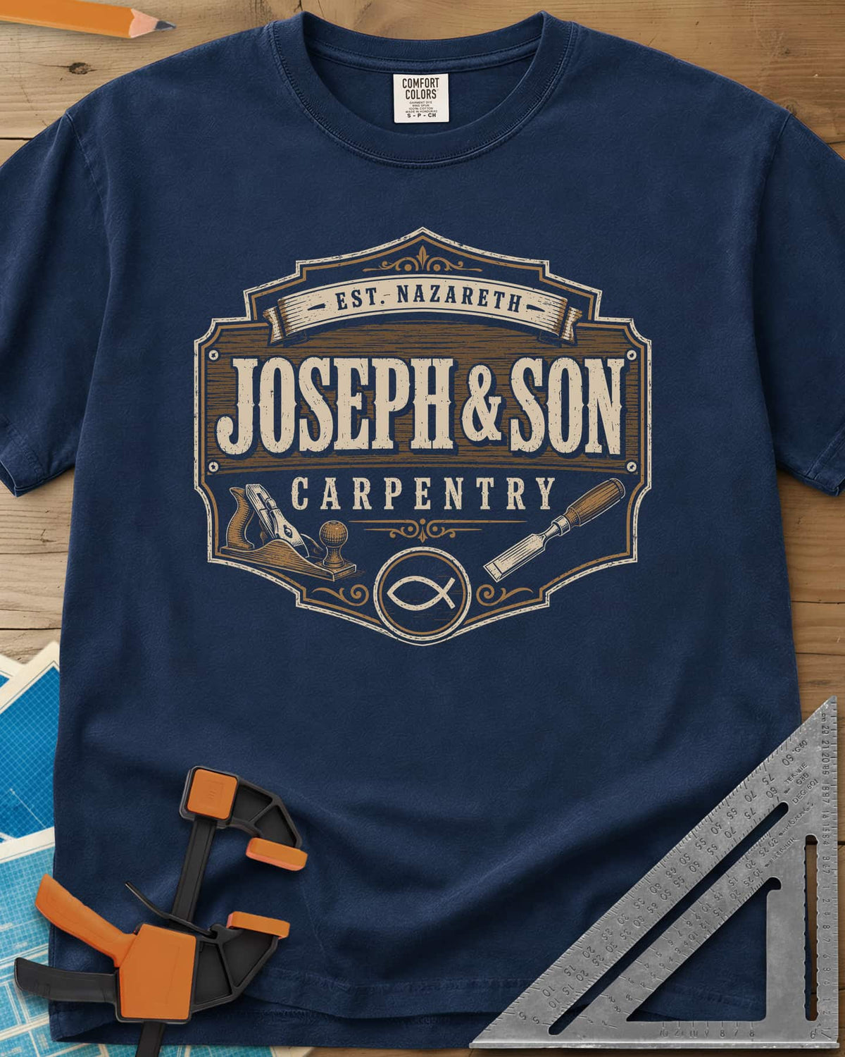 Joseph & Son Carpentry heavyweight tee in Navy, a shop-sign badge with a hand plane, chisel and fish symbol