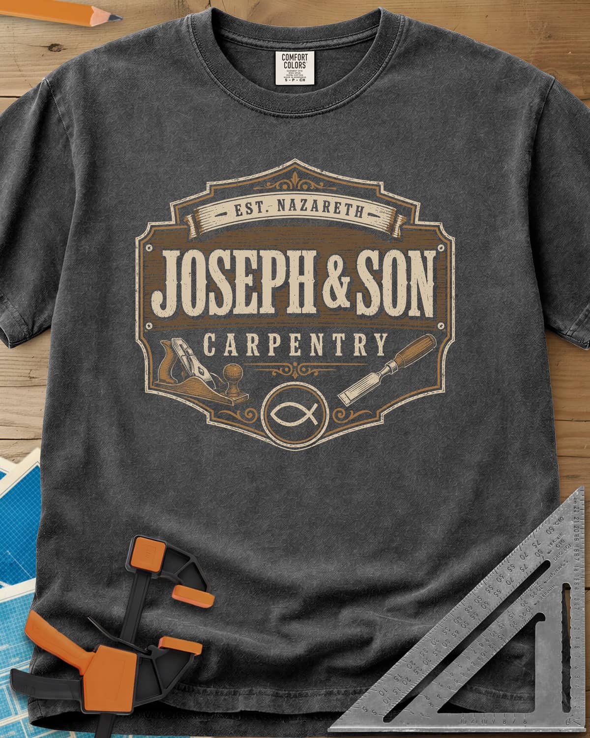 Joseph & Son Carpentry heavyweight tee in Pepper, a shop-sign badge with a hand plane, chisel and fish symbol