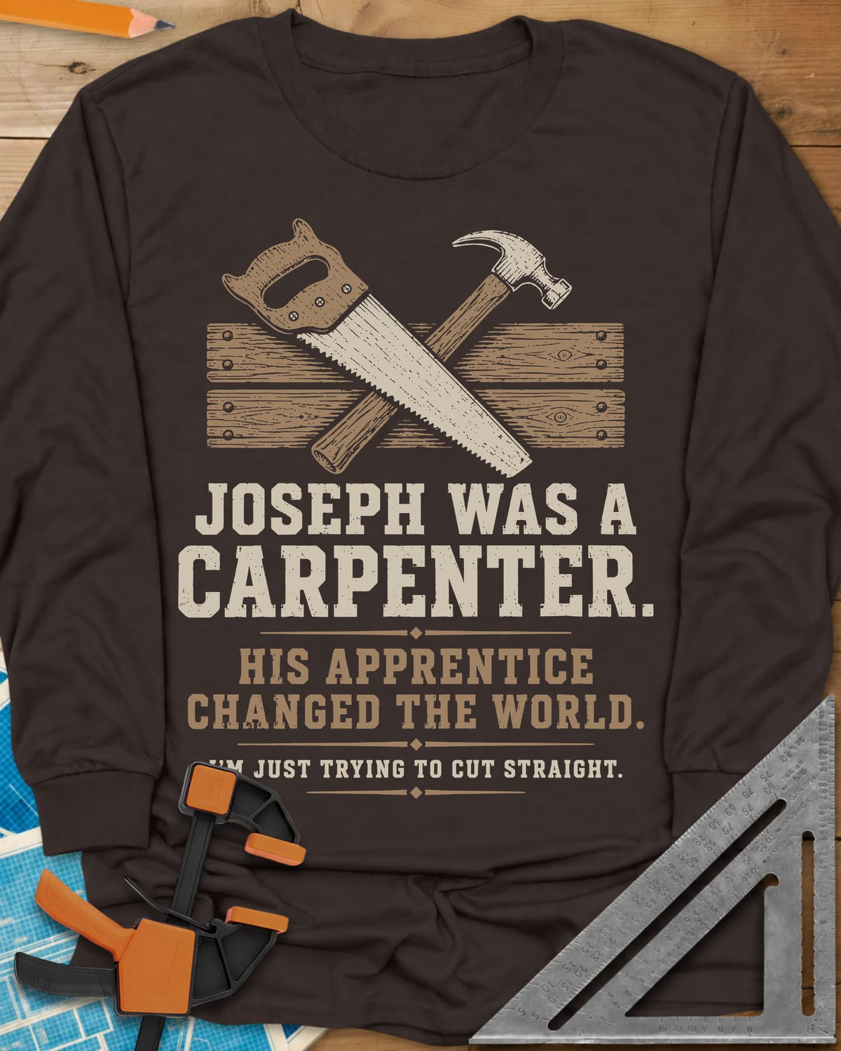 Joseph Was A Carpenter long sleeve shirt in Dark Chocolate, a crossed hand saw and hammer over two weathered boards