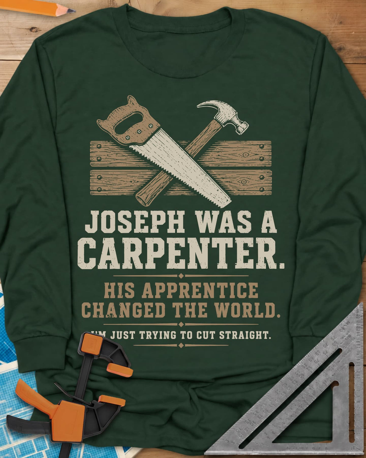 Joseph Was A Carpenter long sleeve shirt in Forest Green, a crossed hand saw and hammer over two weathered boards