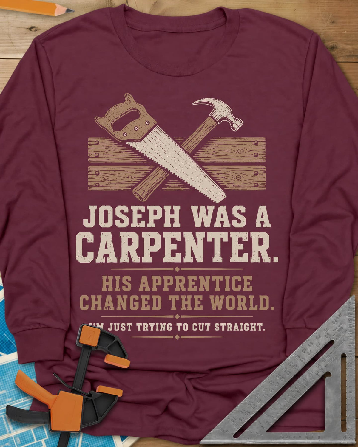 Joseph Was A Carpenter long sleeve shirt in Maroon, a crossed hand saw and hammer over two weathered boards