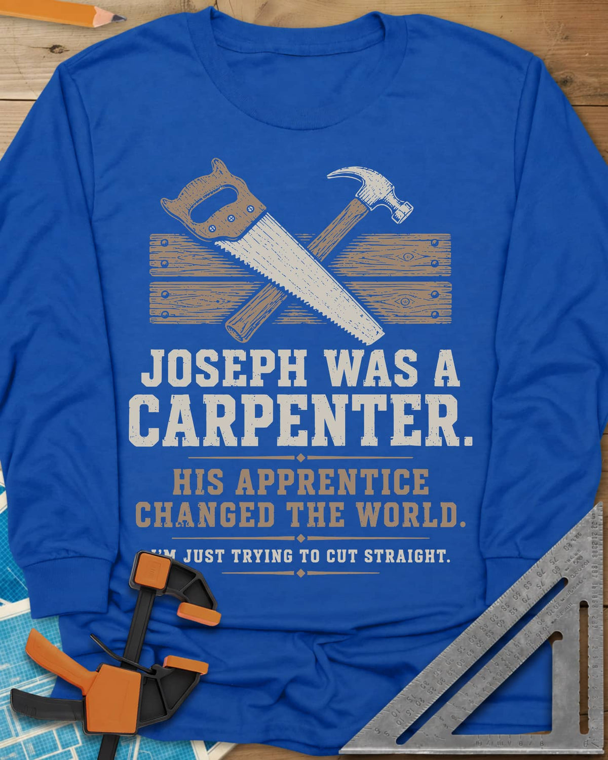 Joseph Was A Carpenter long sleeve shirt in Royal, a crossed hand saw and hammer over two weathered boards