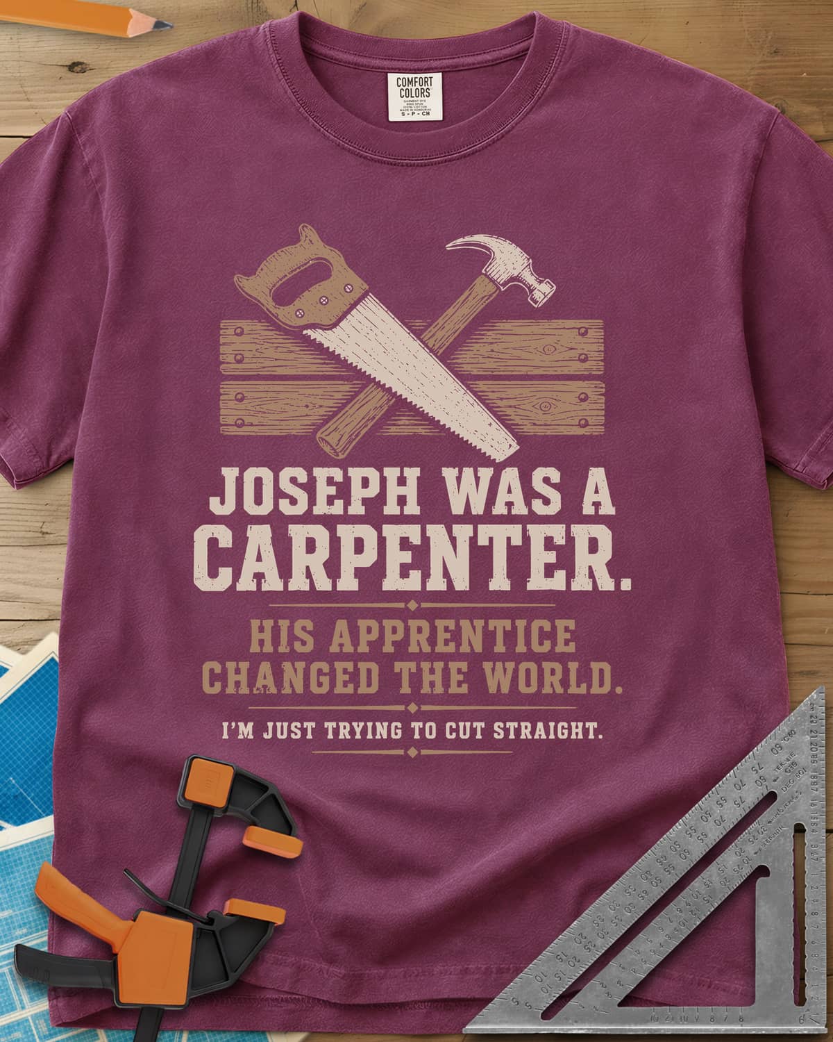 Joseph Was A Carpenter heavyweight tee in Berry, a crossed hand saw and hammer over two weathered boards