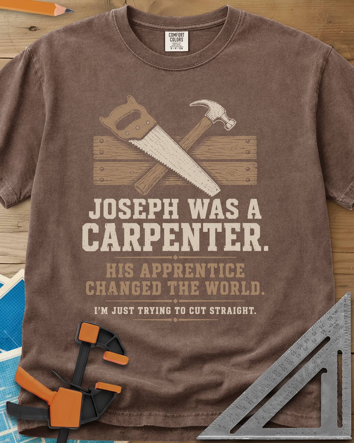 Joseph Was A Carpenter heavyweight tee in Espresso, a crossed hand saw and hammer over two weathered boards