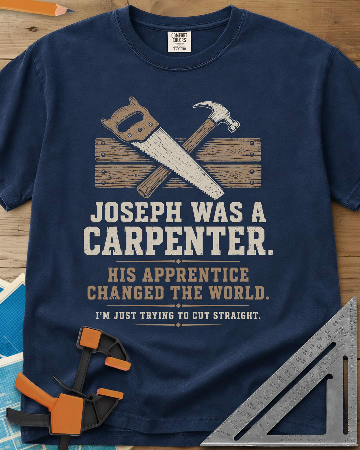Joseph Was A Carpenter heavyweight tee in Navy, a crossed hand saw and hammer over two weathered boards